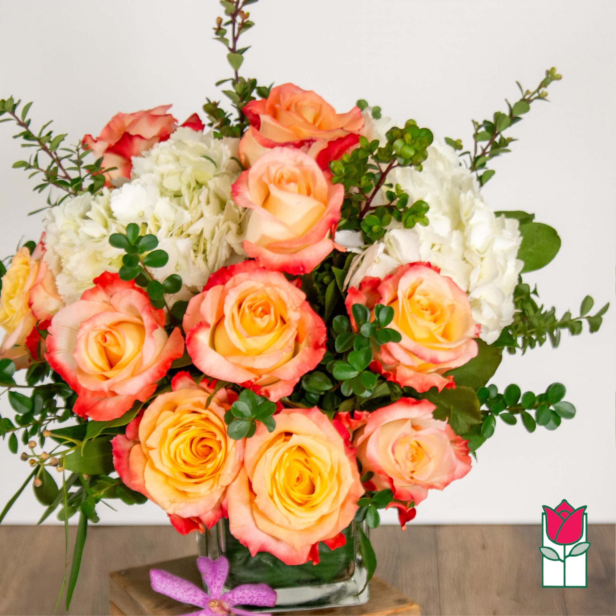 Bouquet of peach and pink roses with white hydrangeas in a glass vase