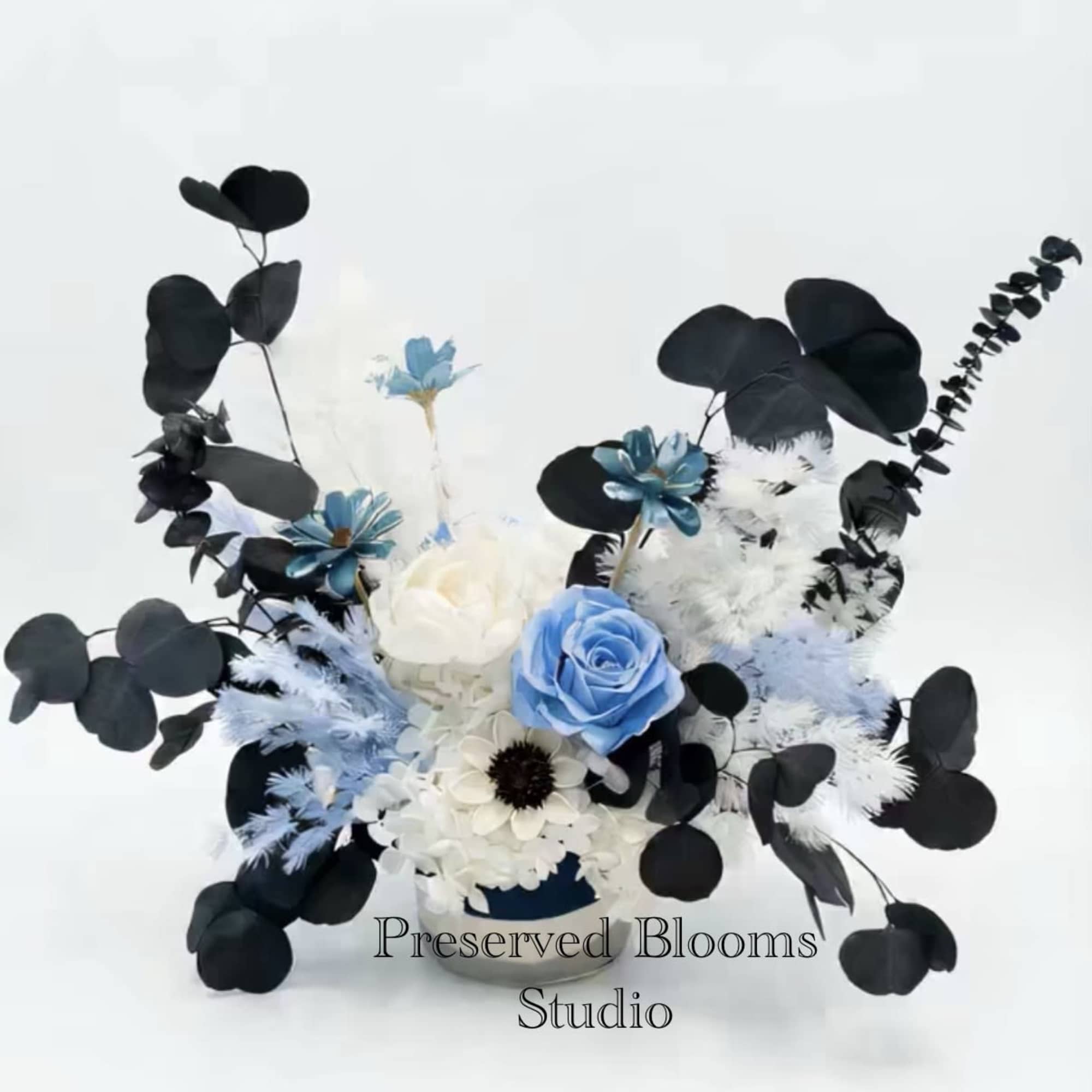 Asymmetrical arrangement of blue and white flowers with black foliage in a low container