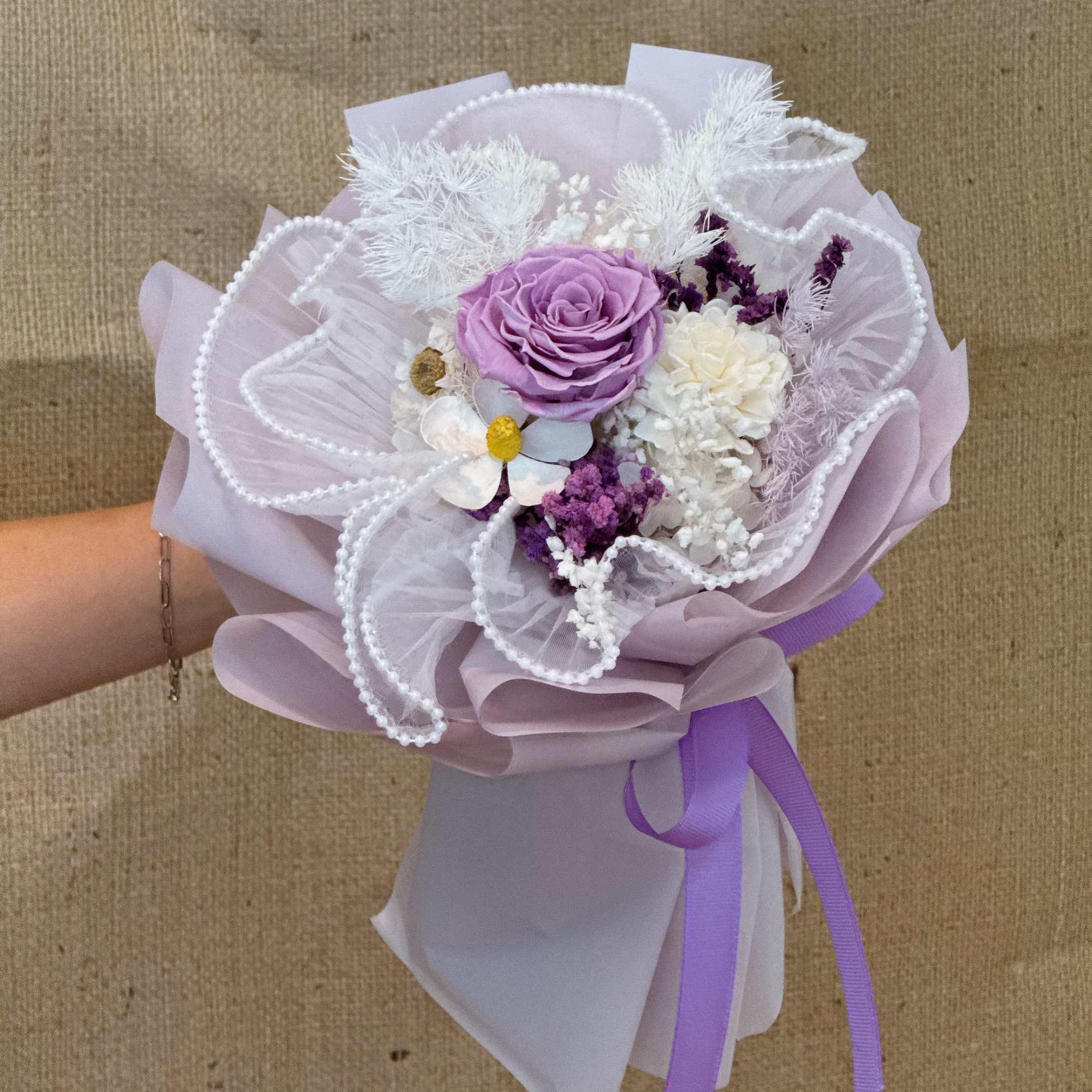Handheld bouquet with lavender rose, white blooms, pearl accents and purple ribbon wrap