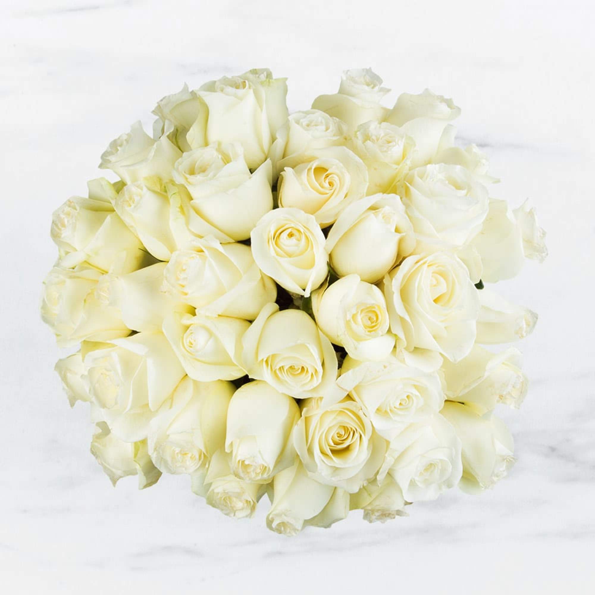 Round bouquet of cream and white roses viewed from above on a light background