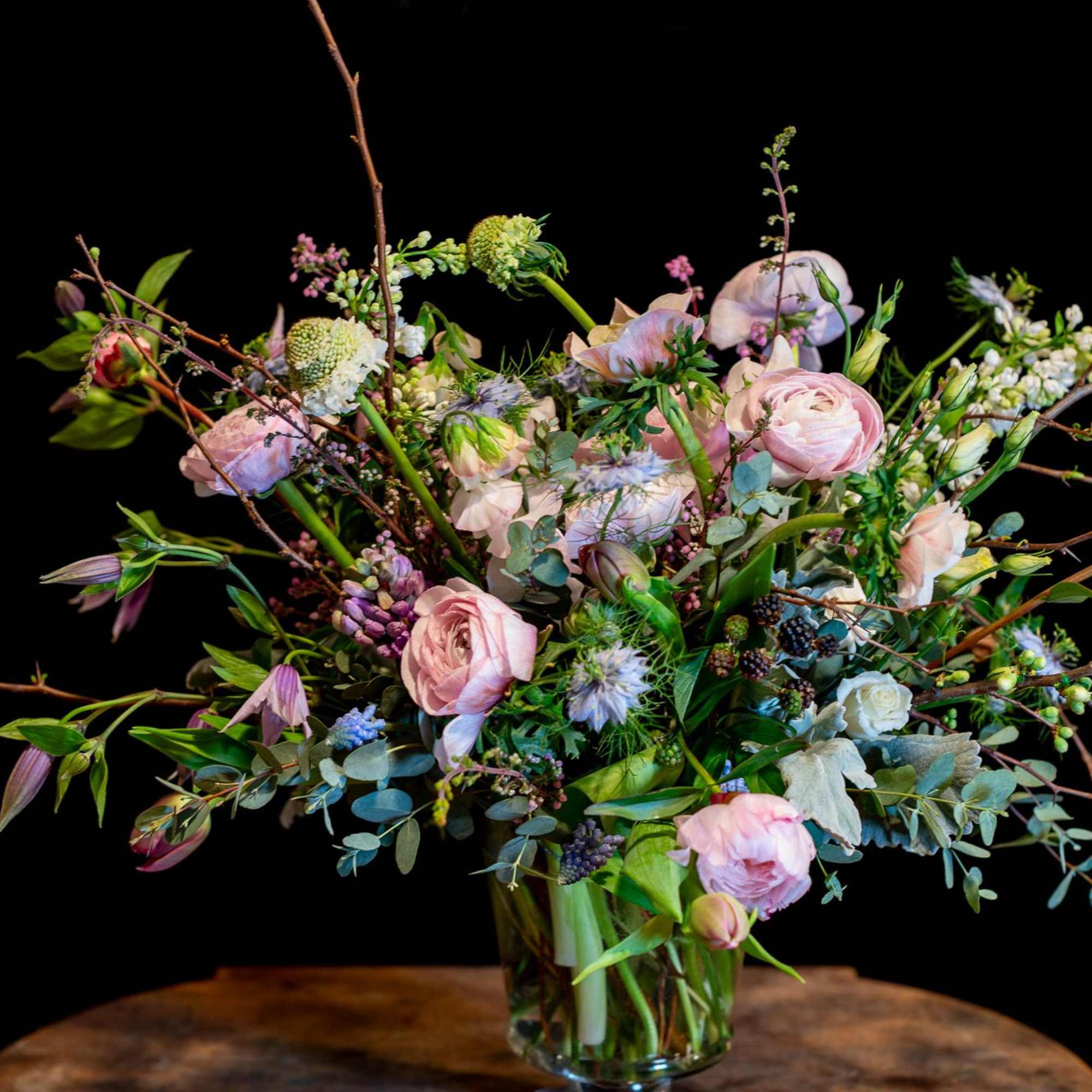 A Dutch Masters inspired spring design using flowering branches, premium ranunculus, peonies