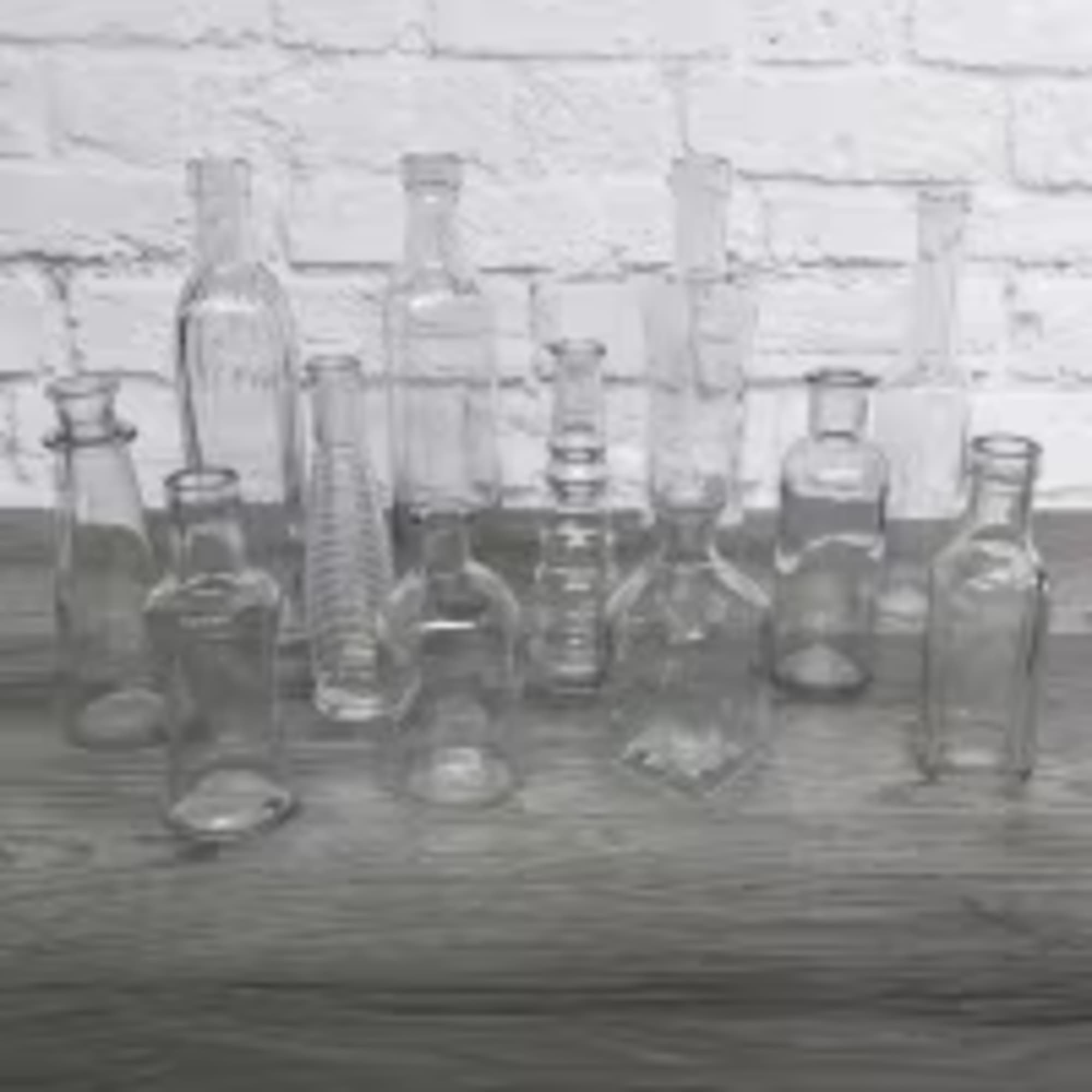 Assorted clear glass bottles and jars arranged on a wooden surface
