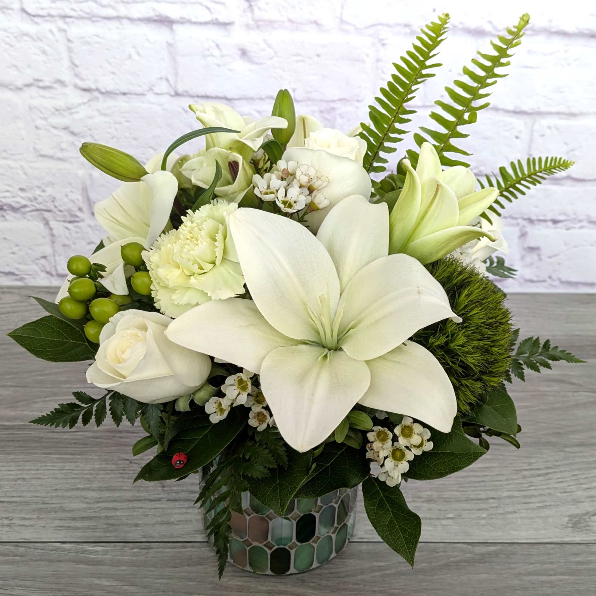 White lilies and roses arranged in a mosaic vase