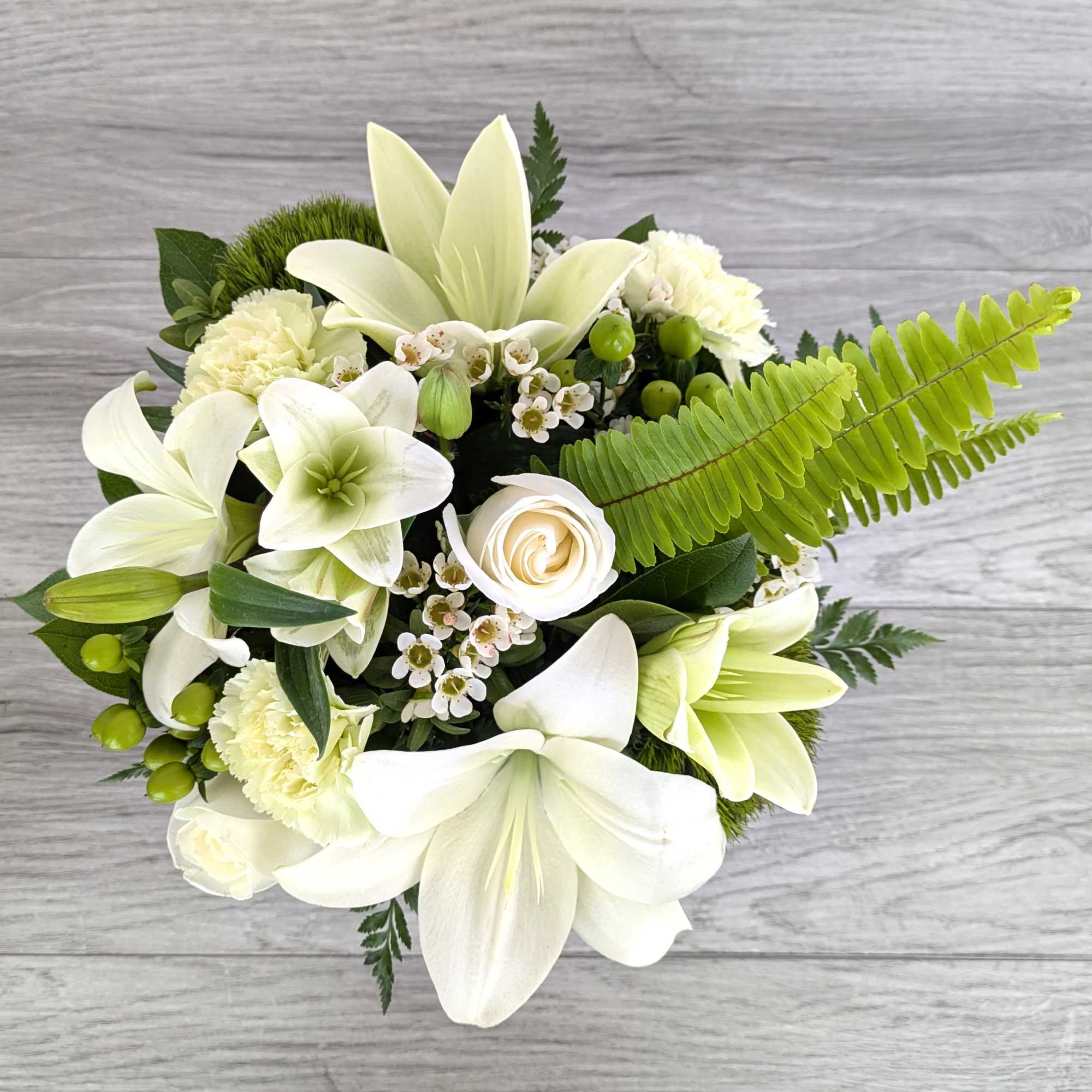 White lilies and roses arranged with green accents.