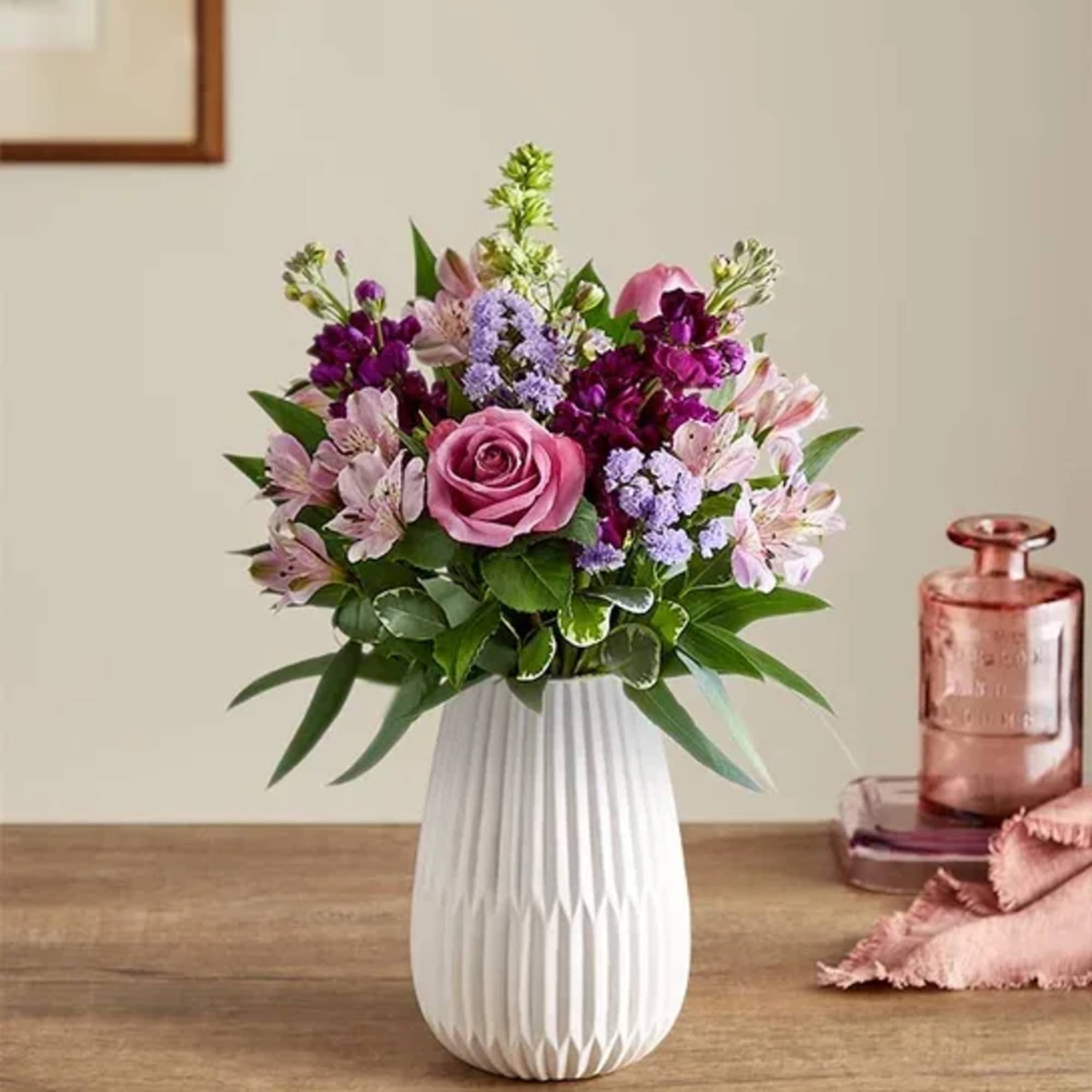 Mixed pink and purple flower arrangement with a rose and alstroemeria in a white ceramic vase