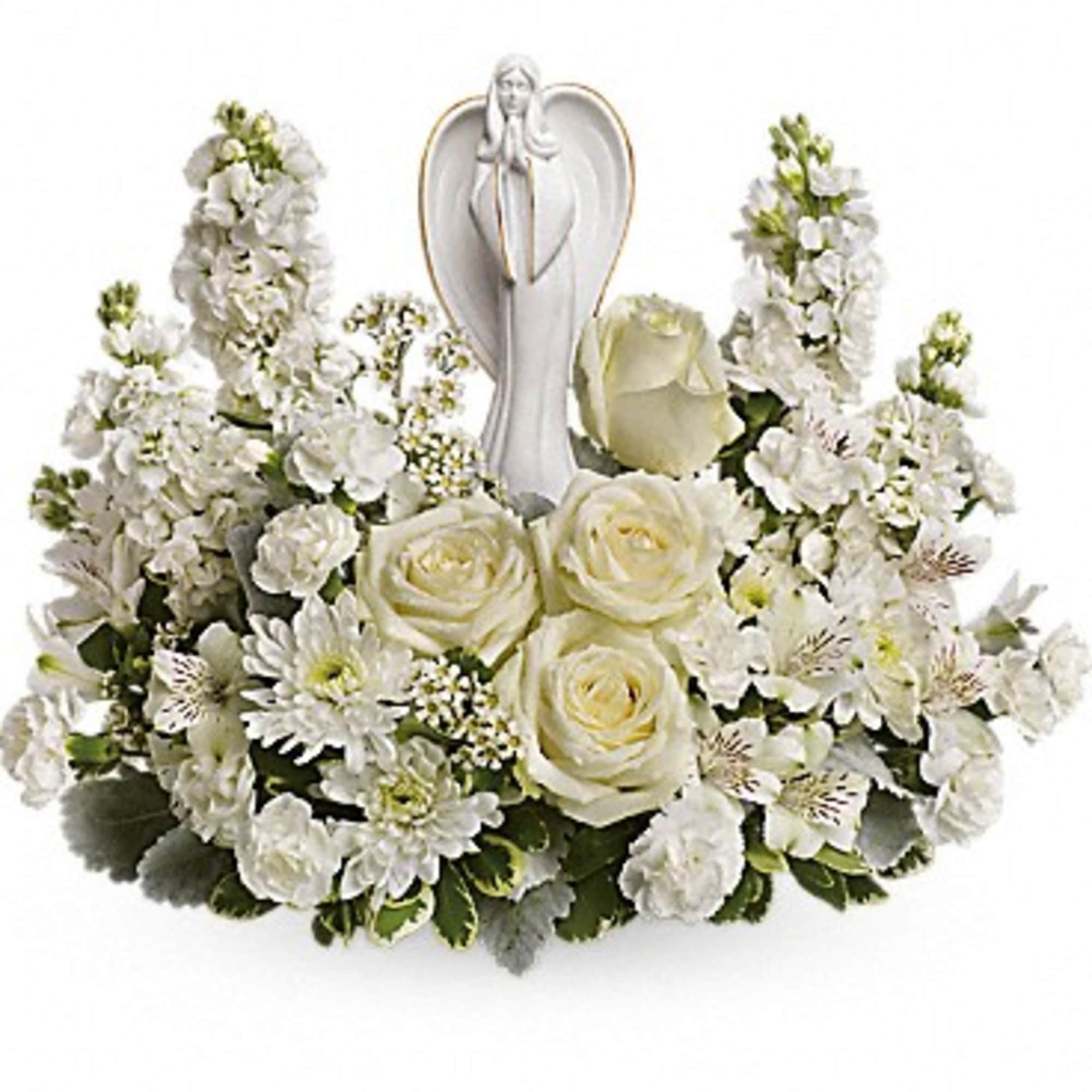 Low white floral arrangement with roses and mixed blooms surrounding a white ceramic angel figurine.