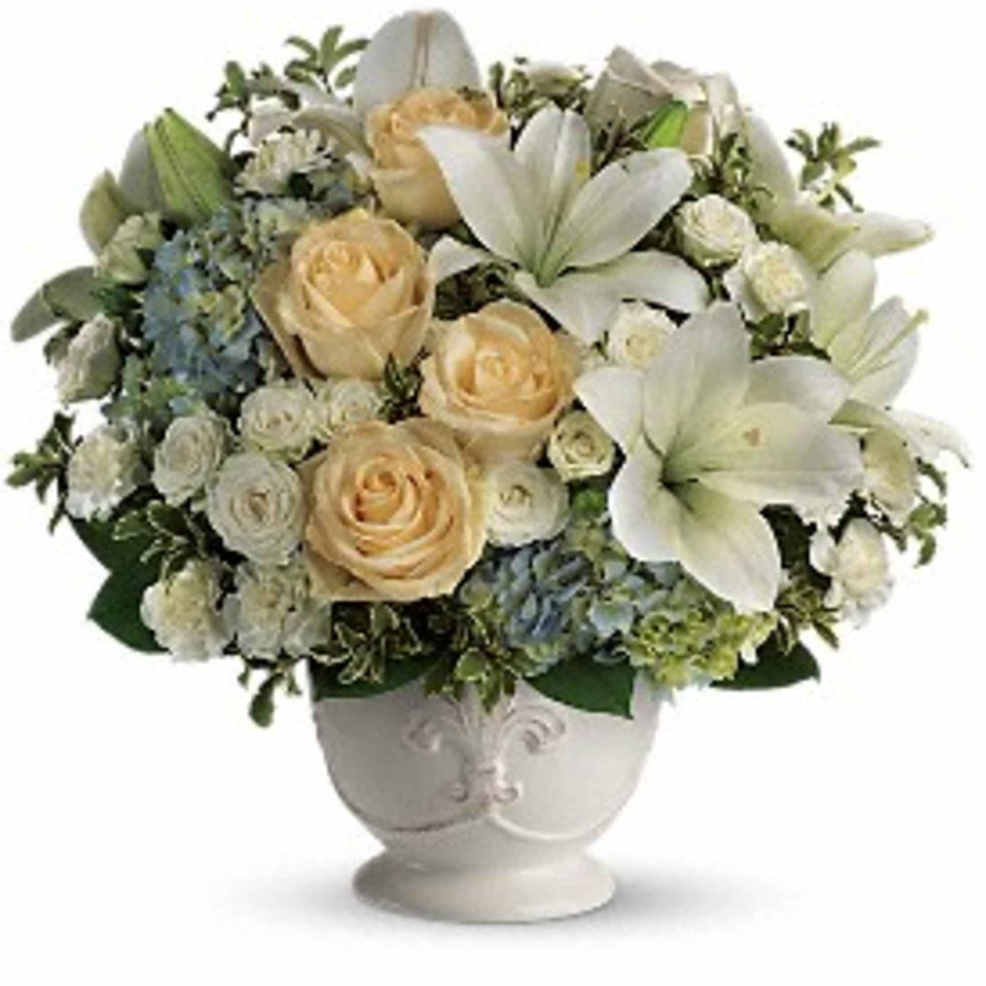 Compact arrangement of cream roses, white lilies, and blue hydrangeas in a white pedestal vase
