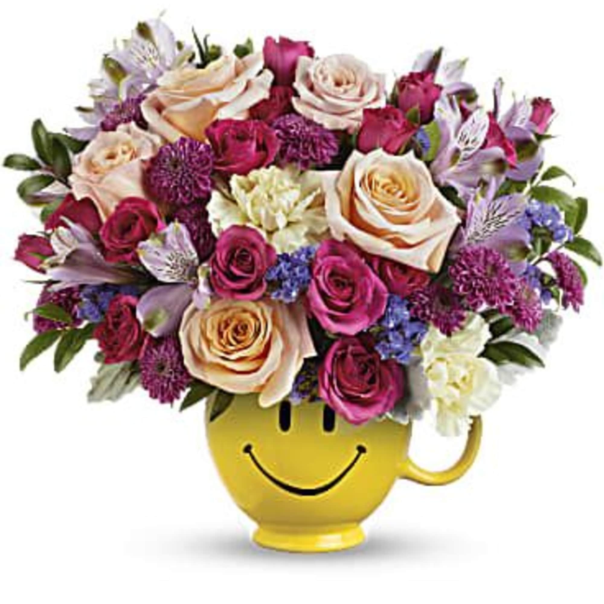 Colorful mixed bouquet of roses and other blooms in a yellow smiley-face mug