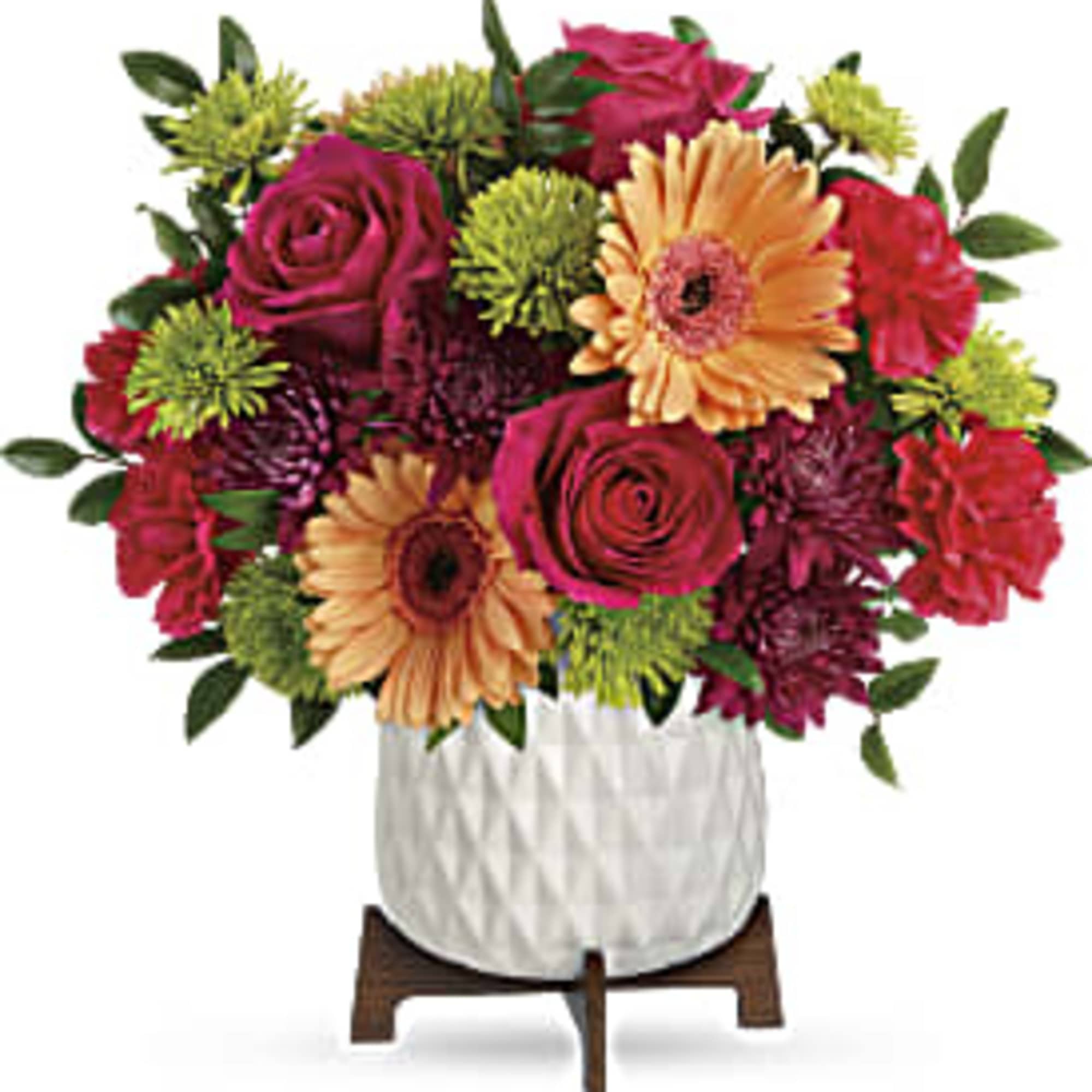 Bright mixed bouquet of pink roses, peach gerbera daisies, and green mums in a white ceramic pot on a wooden stand