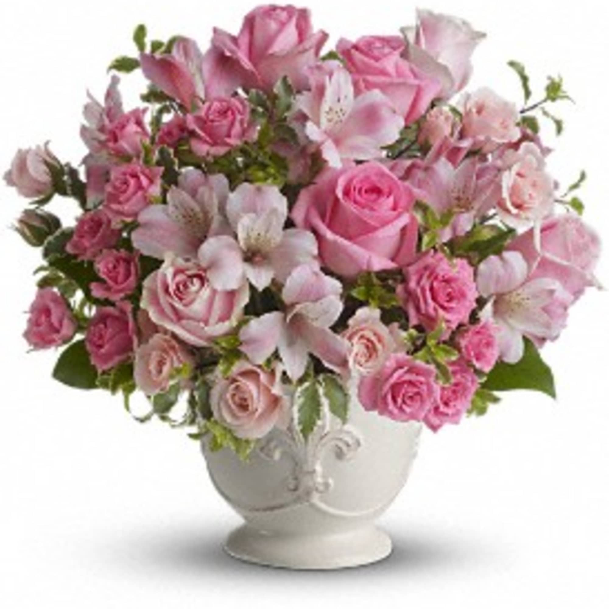 Pink roses and alstroemeria arranged in a rounded bouquet in a white ceramic pedestal vase