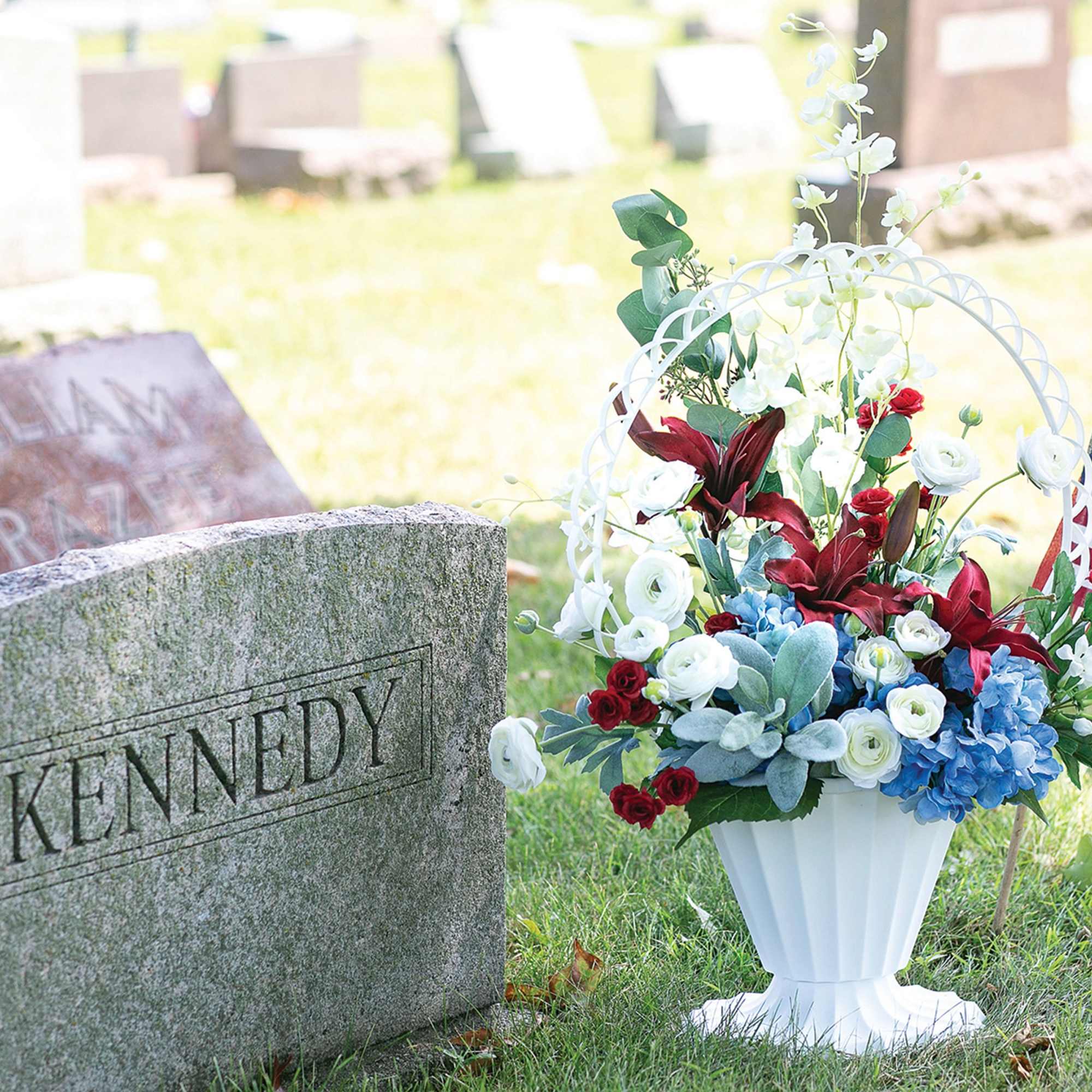 Floral grave arrangement in a white urn beside a Kennedy headstone