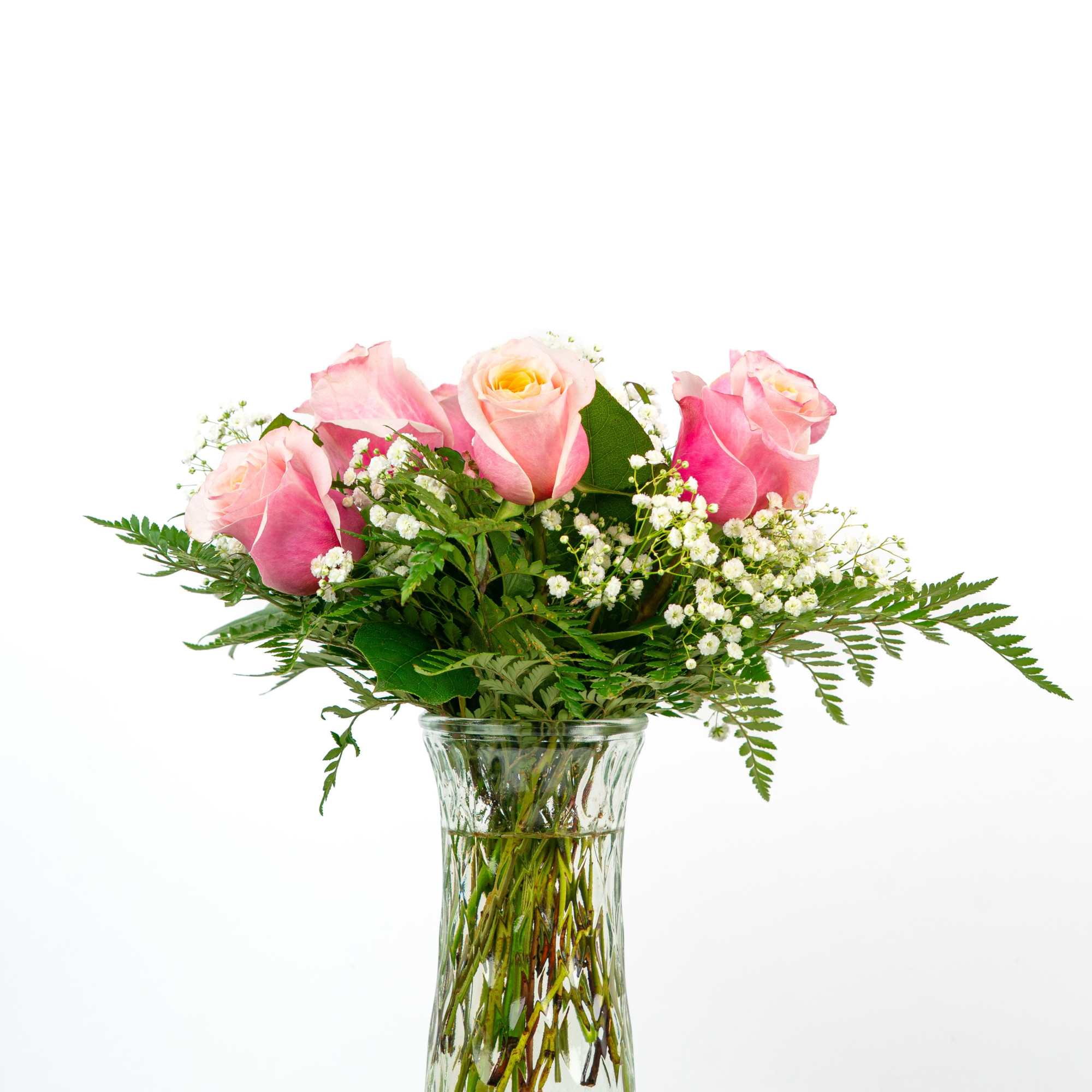 Pink roses with white filler flowers in a clear glass vase