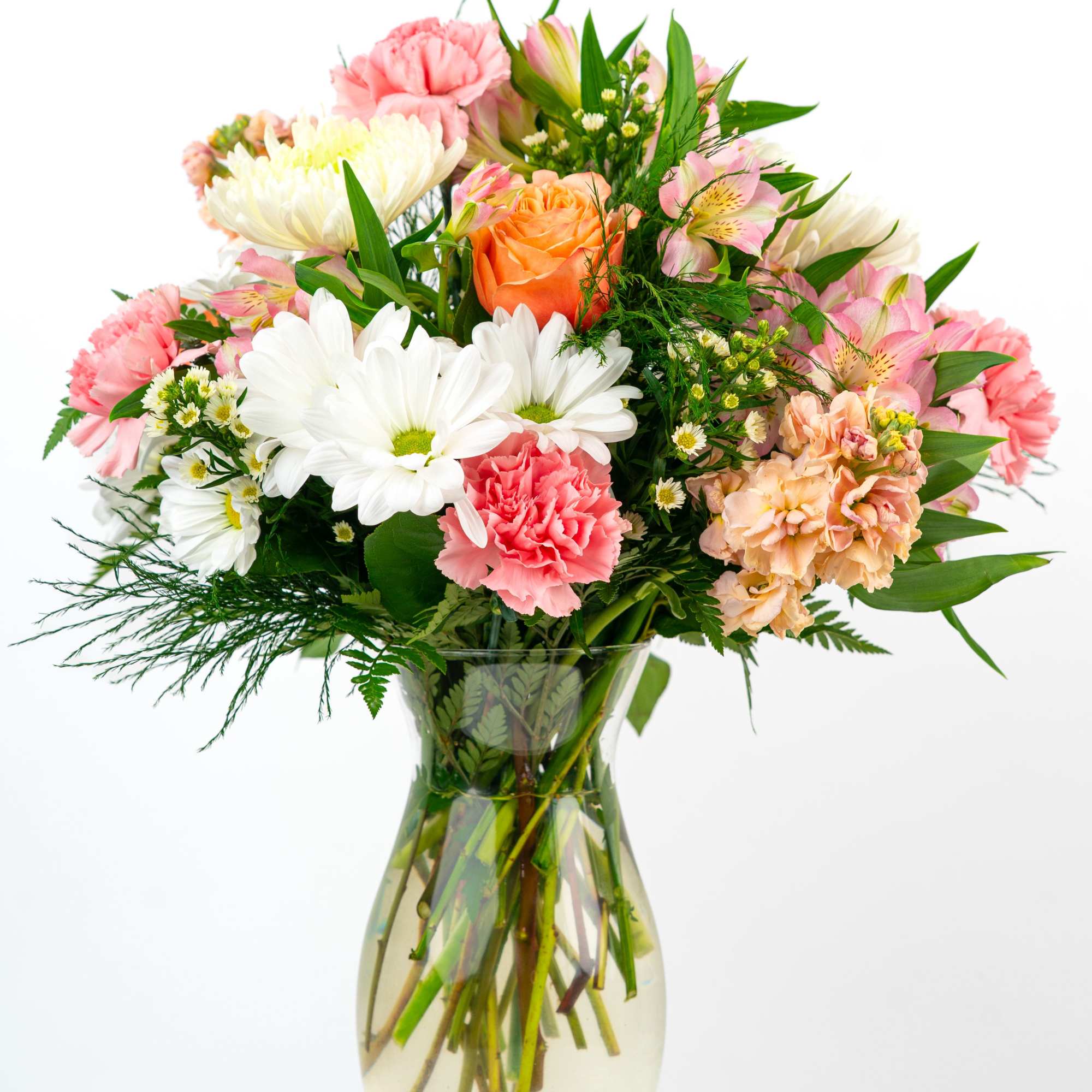 Mixed bouquet of pink carnations, white daisies, and an orange rose in a clear glass vase