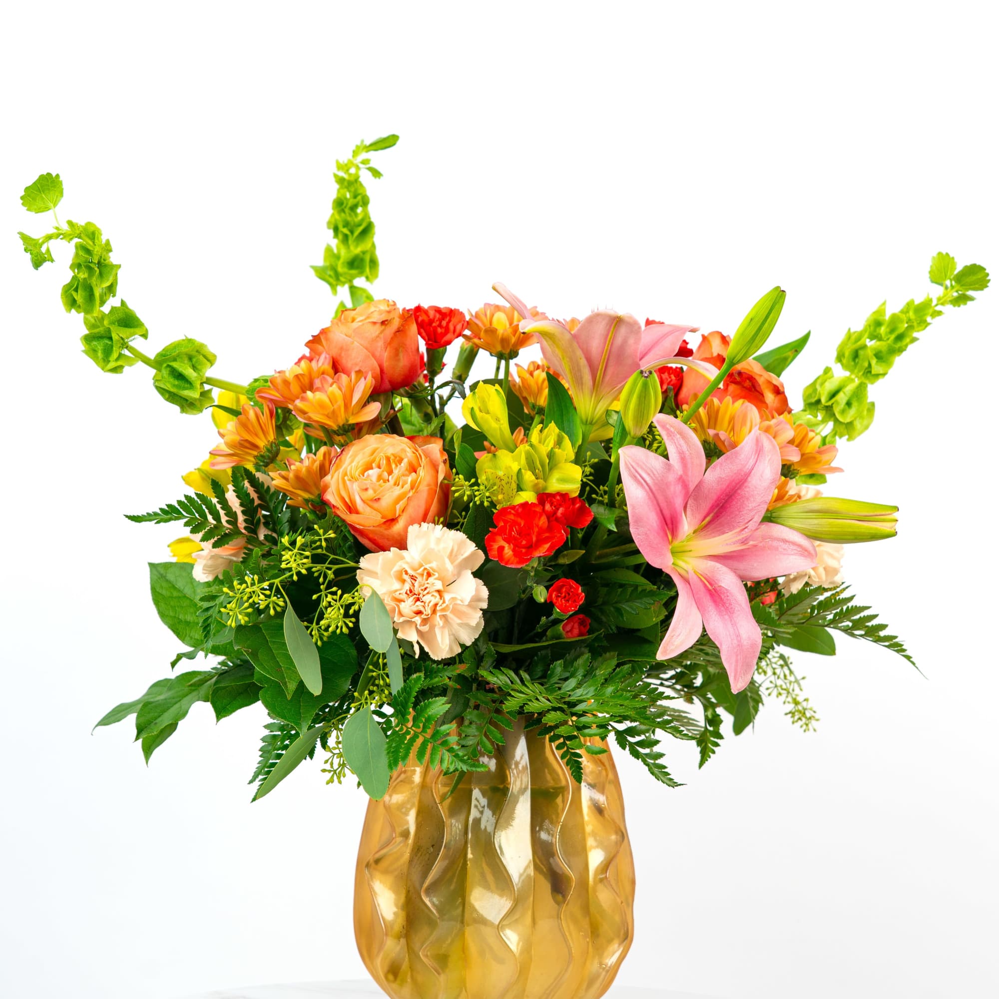 Bright arrangement of pink lilies, orange roses, and mixed blooms in a golden glass vase