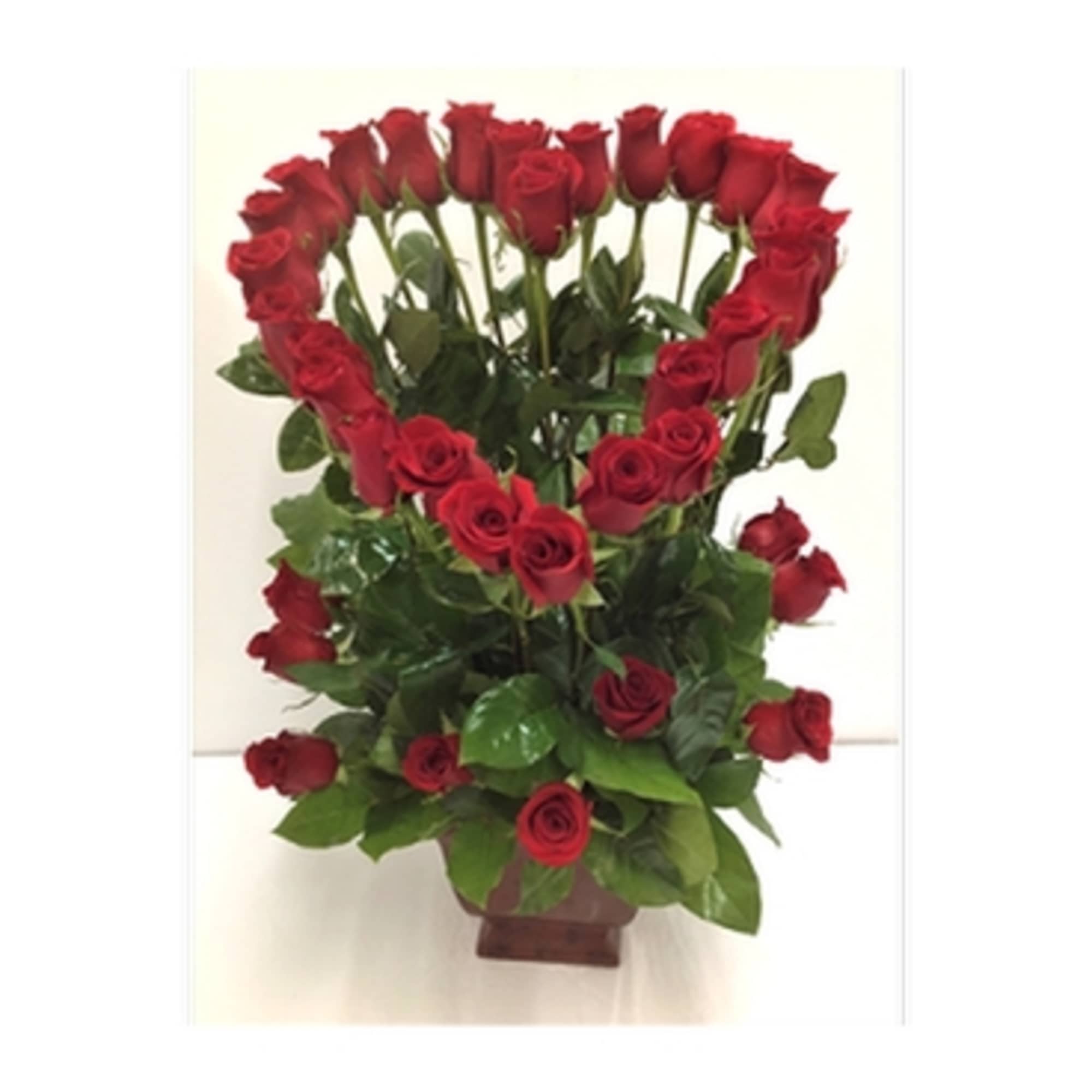 Tall arrangement of red roses shaped into a heart above more roses in a brown vase