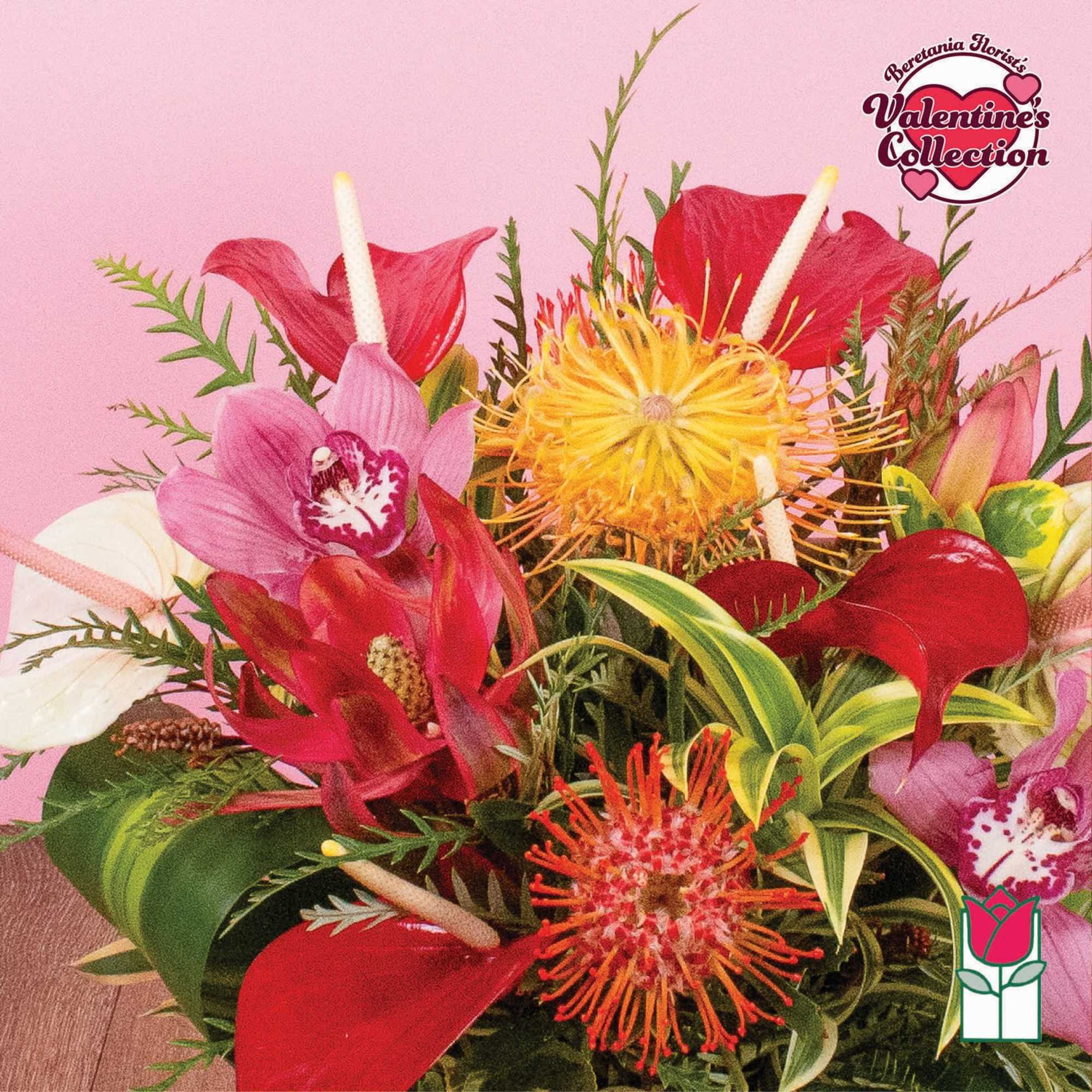 Tropical flower arrangement with red anthuriums, pink orchids, and orange pincushion blooms on a pink background