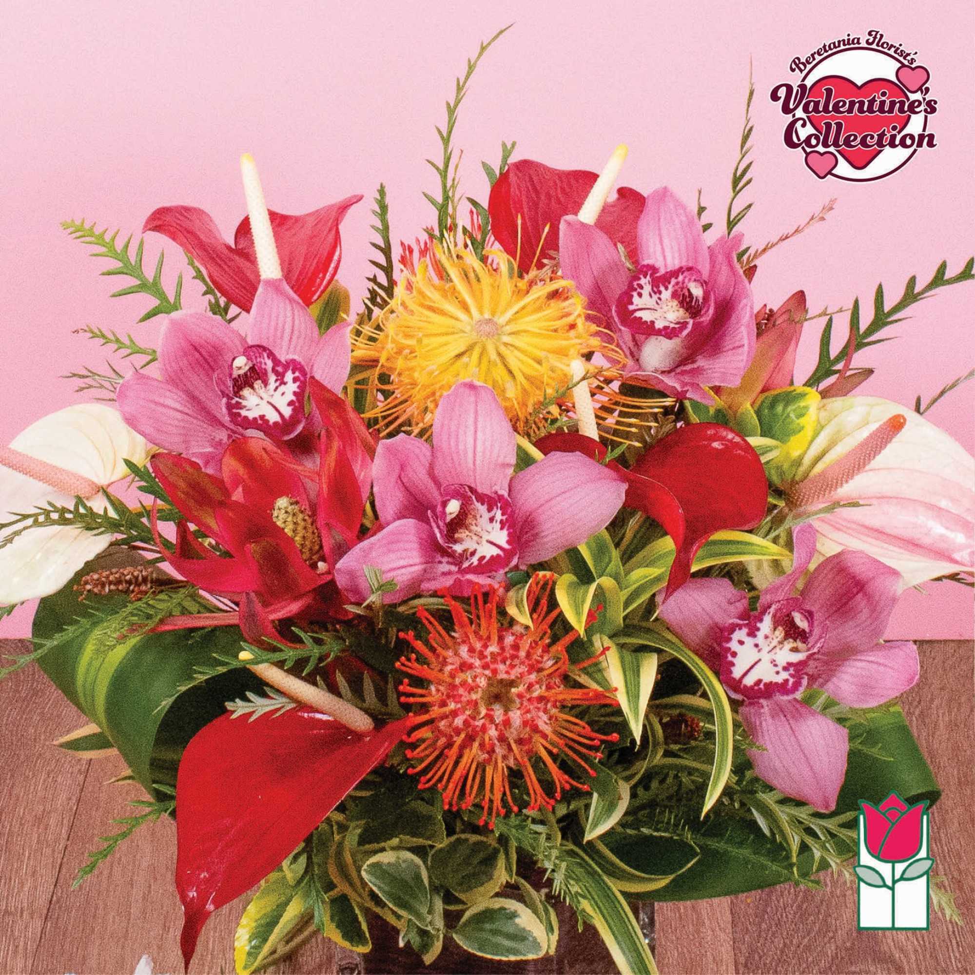 Bright tropical arrangement with pink orchids, red and white blooms in a low glass vase on a pink background