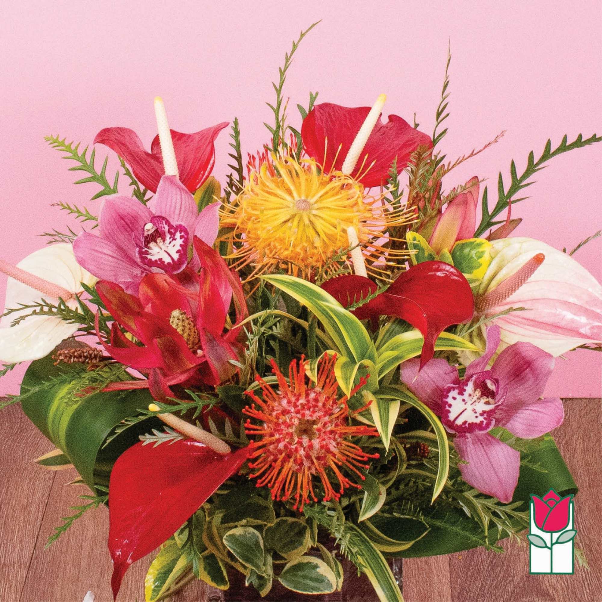 Tropical arrangement with orchids, anthuriums, and pincushion protea in a low vase