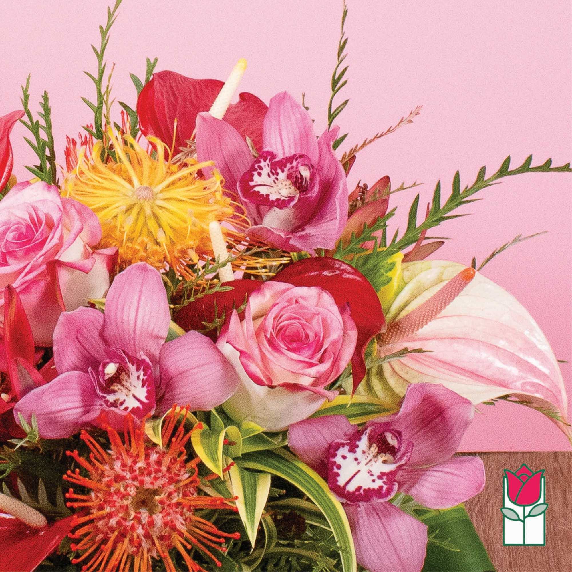 Bright arrangement with pink roses, orchids, protea and tropical blooms against a pink background