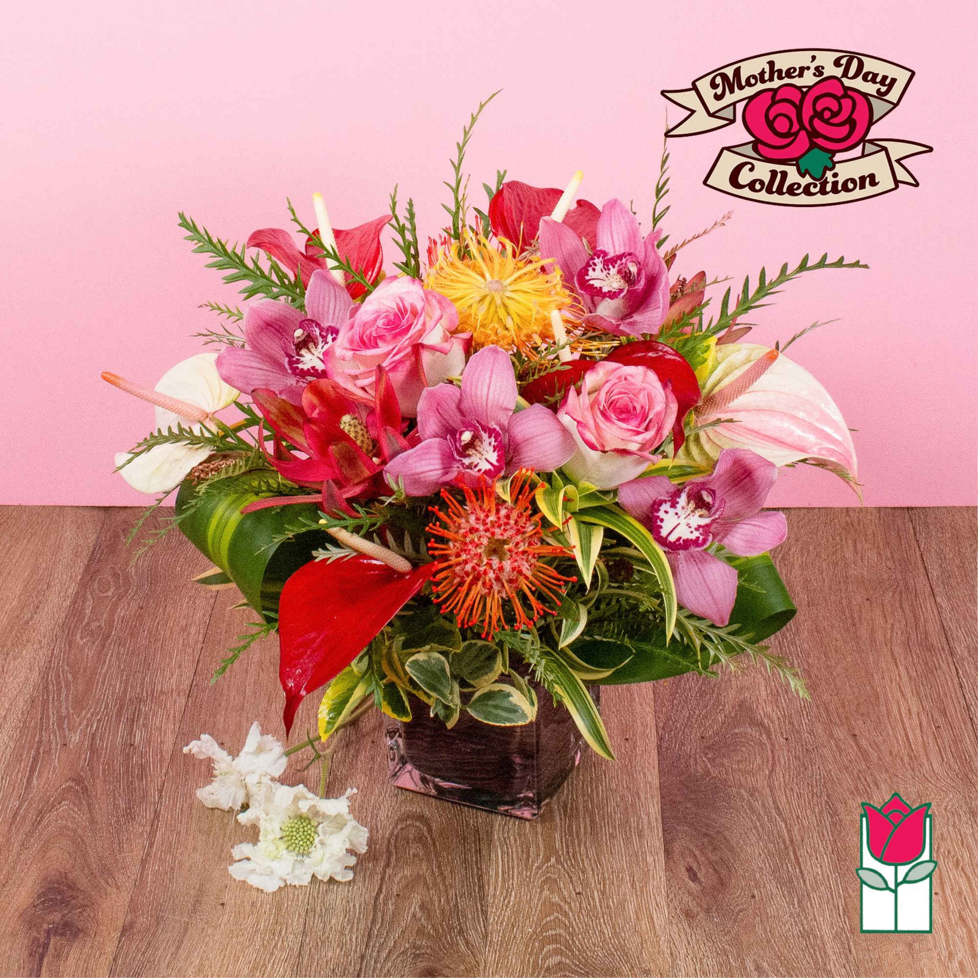 Tropical arrangement with pink roses, orchids, red anthuriums and orange protea in a square glass vase