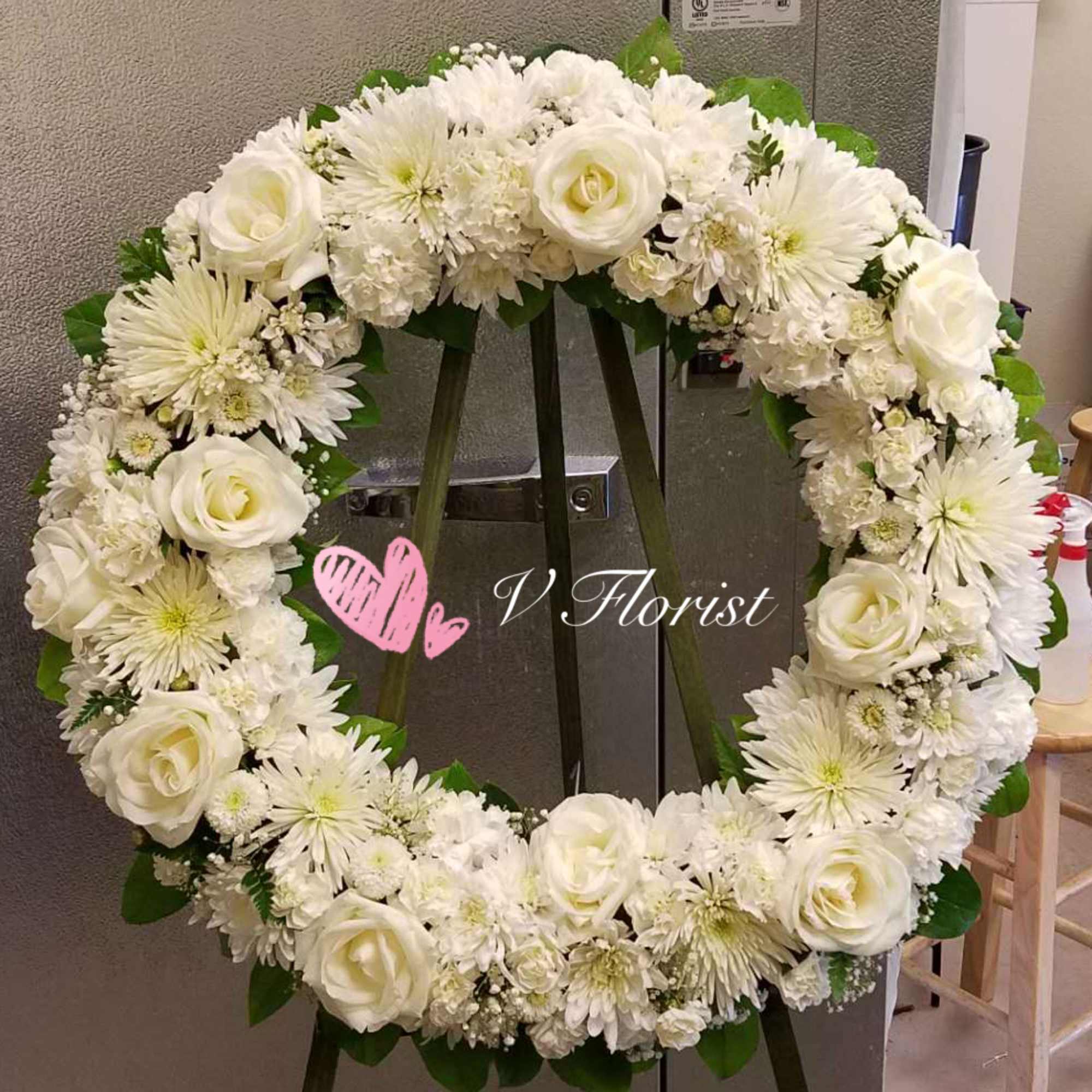 Large white rose and mum wreath displayed on a stand