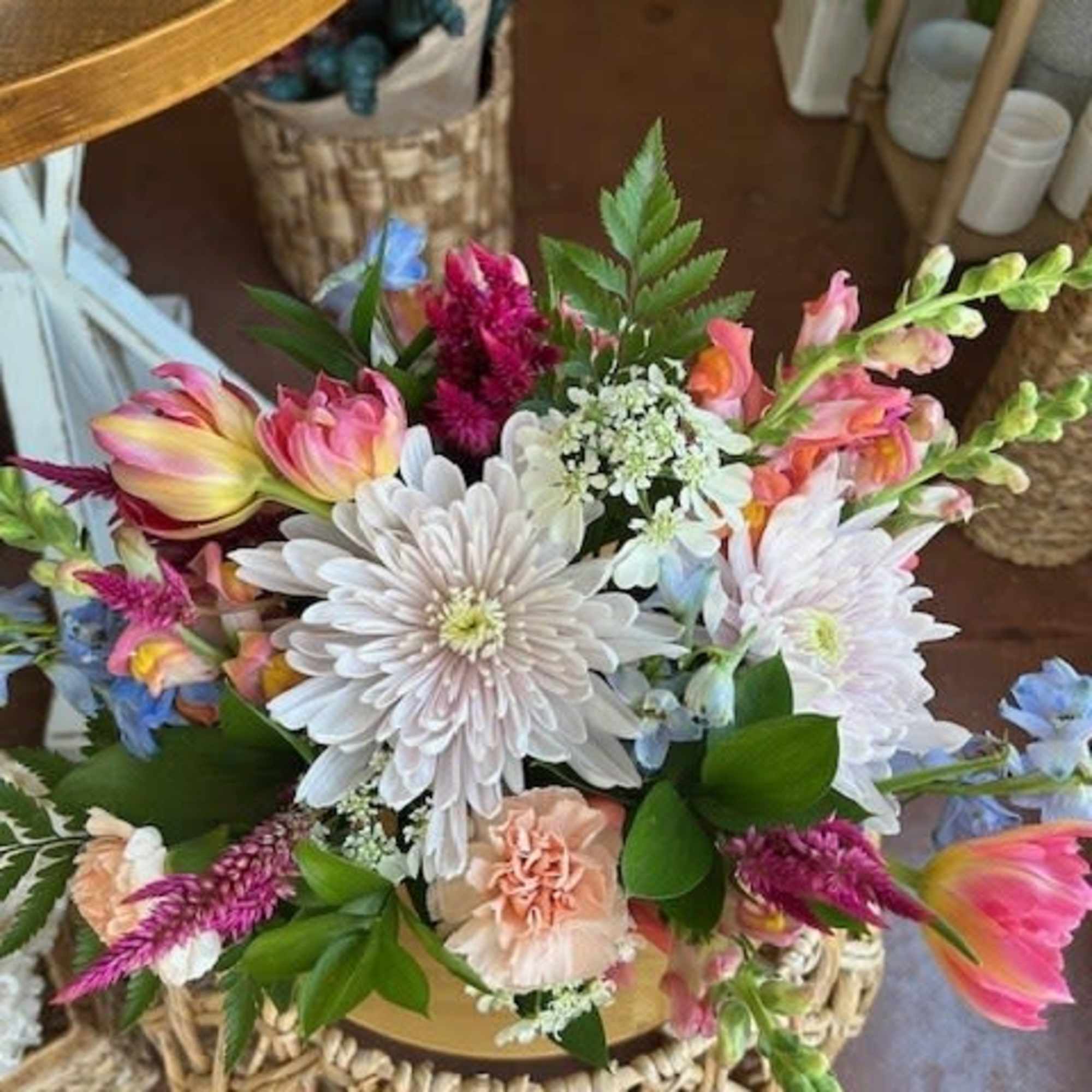 Mixed arrangement of pastel chrysanthemums, carnations, and snapdragons in a round vase