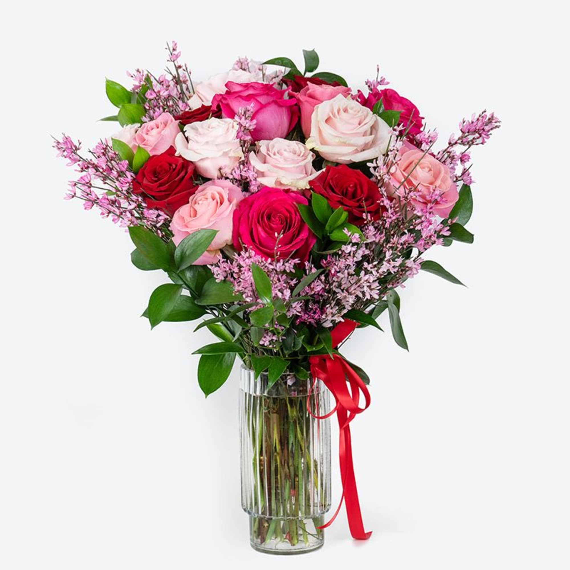 Bouquet of red and pink roses with small pink filler flowers in a clear glass vase