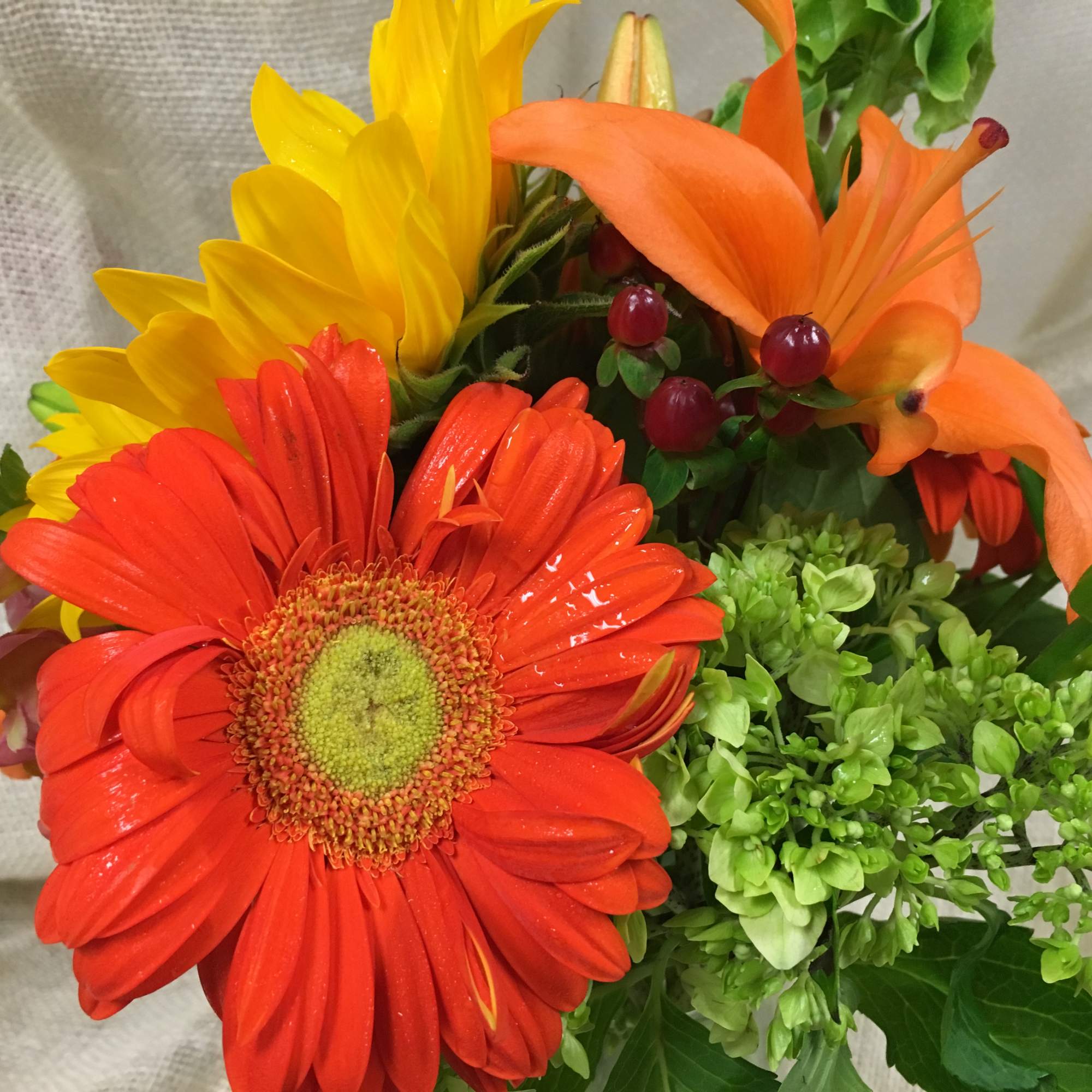 Bright bouquet with red gerbera daisies, yellow sunflowers, and orange lilies