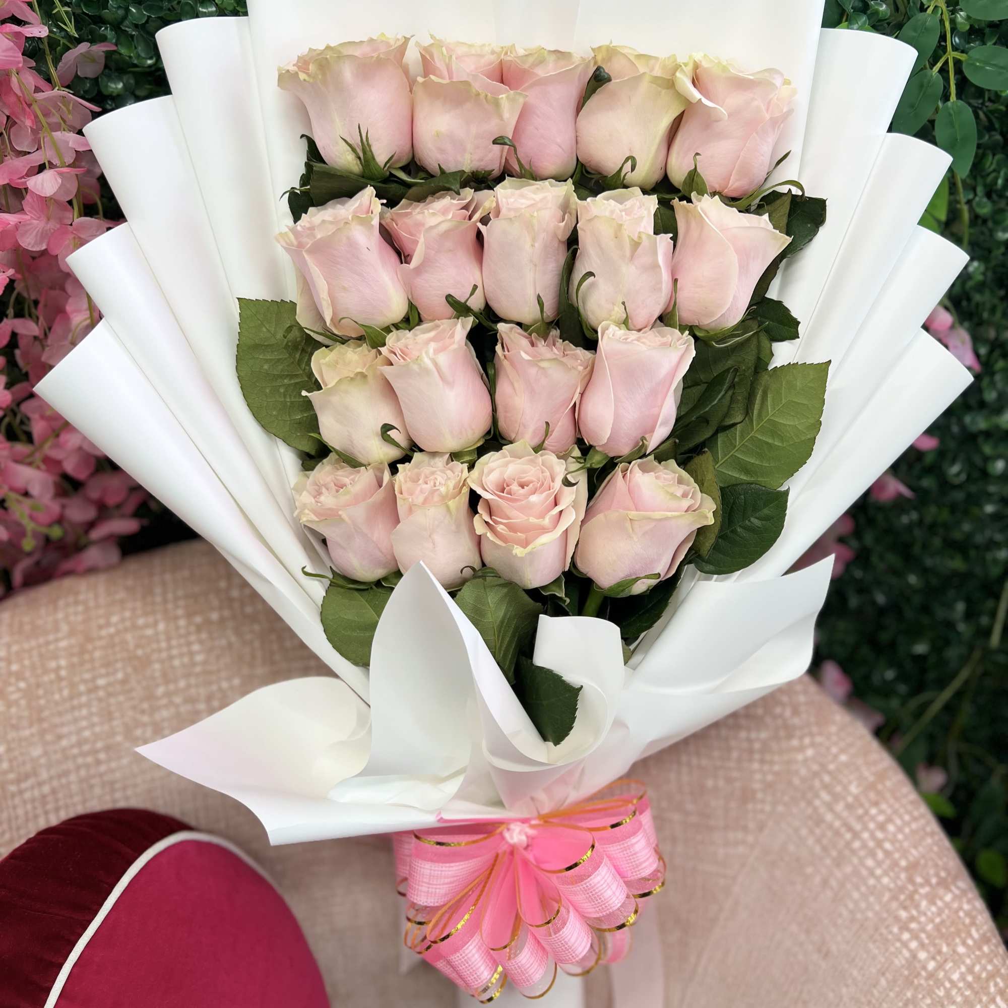 Large bouquet of pale pink roses wrapped in white paper with a pink bow