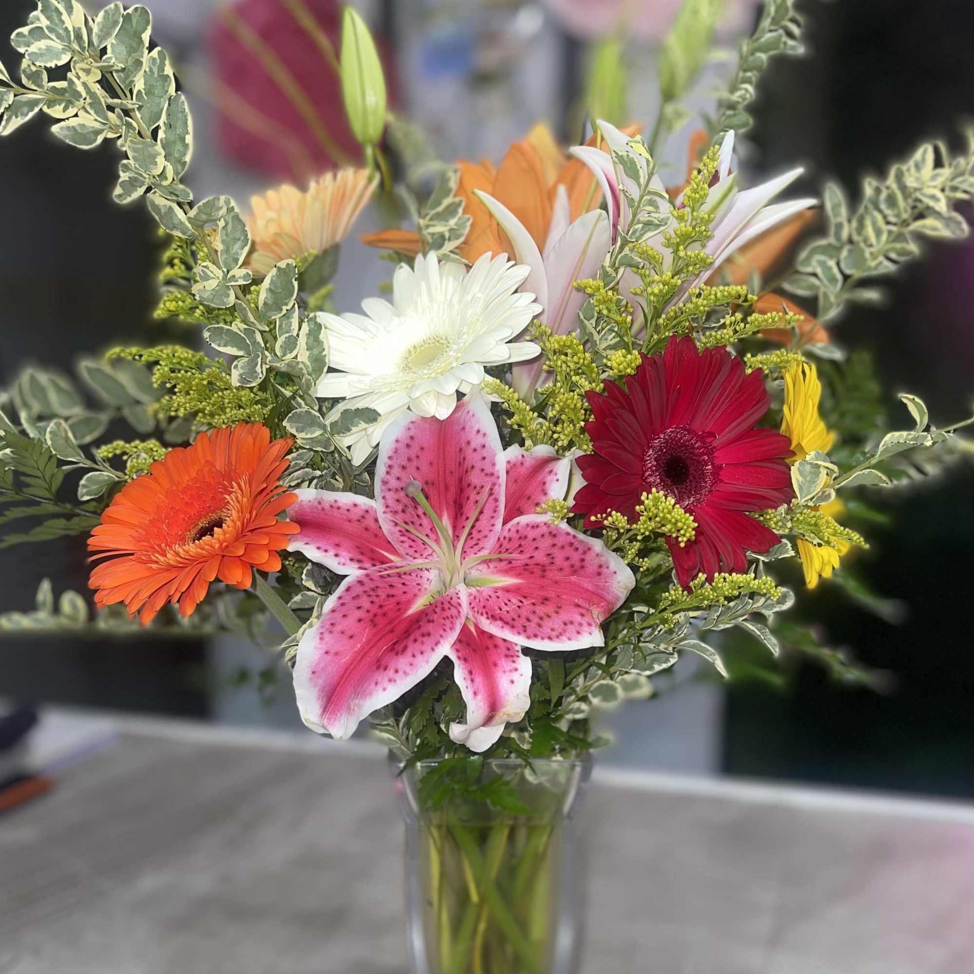 Mixed bouquet with lilies and gerbera daisies in a clear glass vase