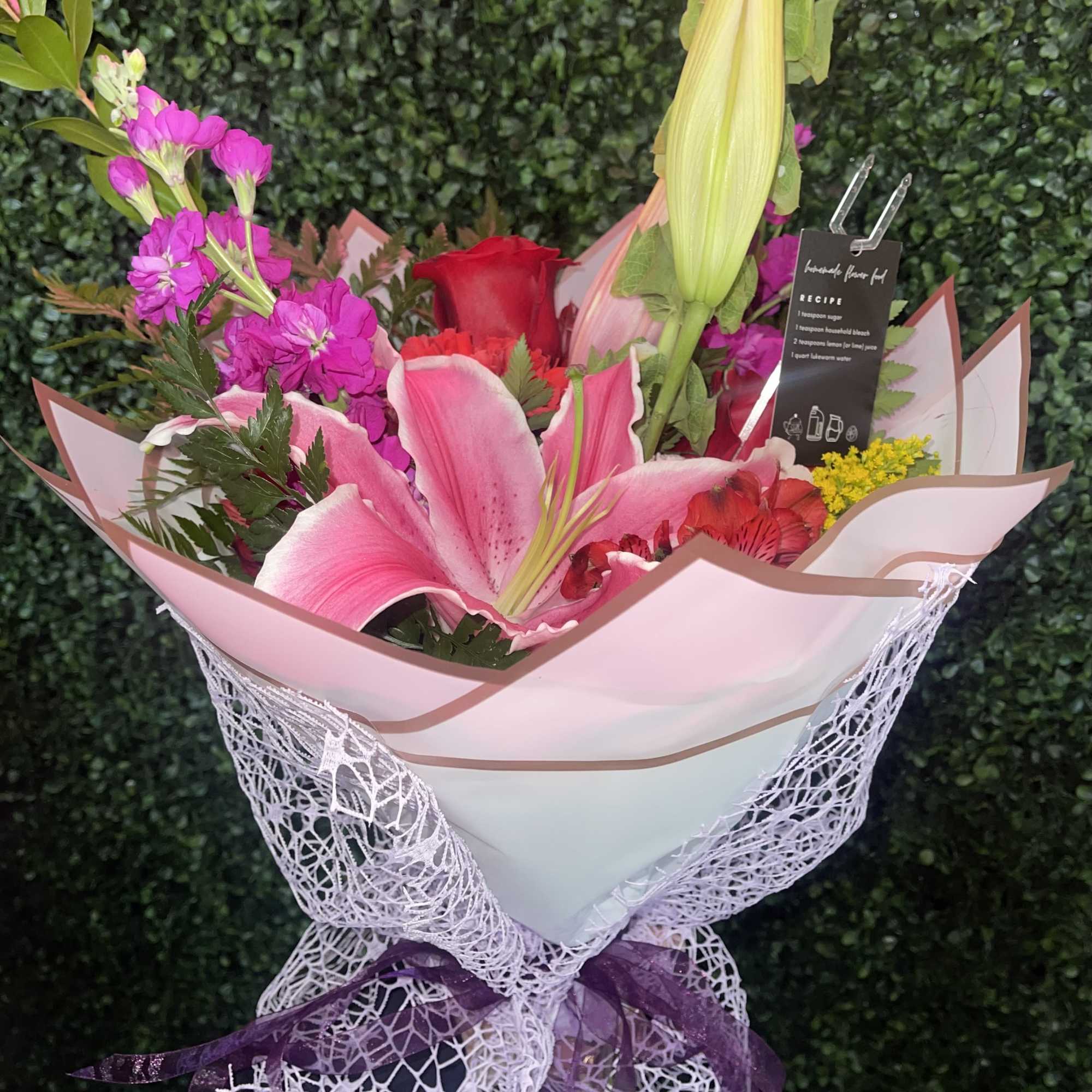 Pink lily bouquet with red and magenta flowers wrapped in white paper