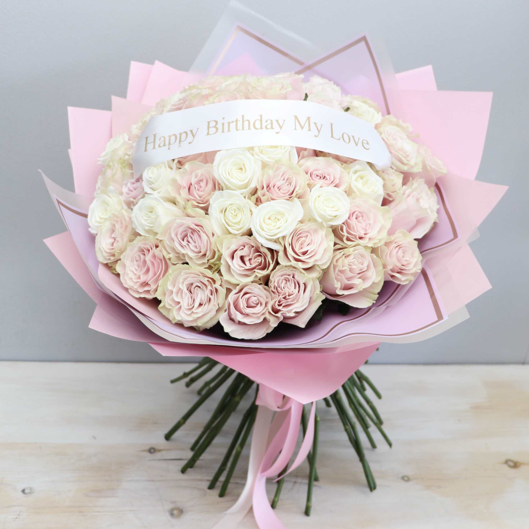 Hand-tied bouquet of pink and white roses with a birthday message in pink wrapping.