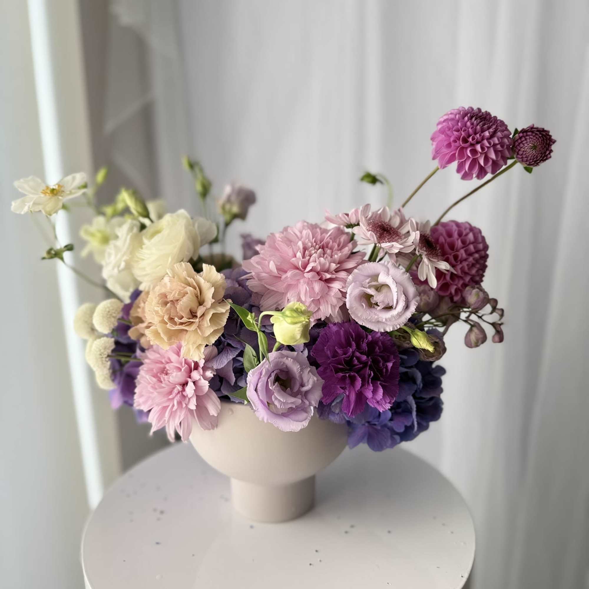 Set in a modern pedestal vase, each stem is placed with intention