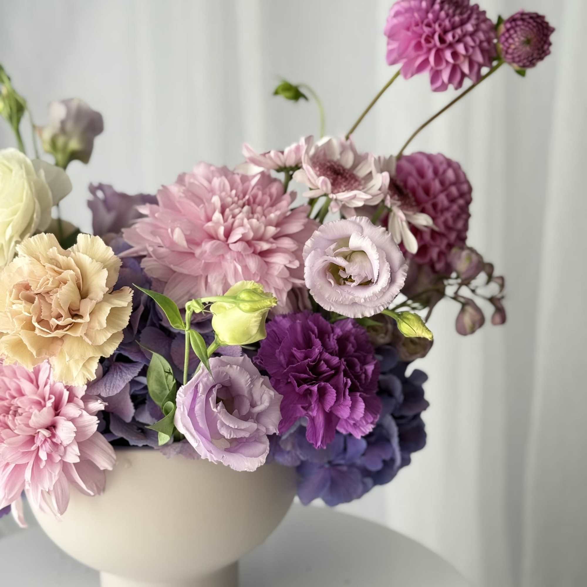 Set in a modern pedestal vase, each stem is placed with intention