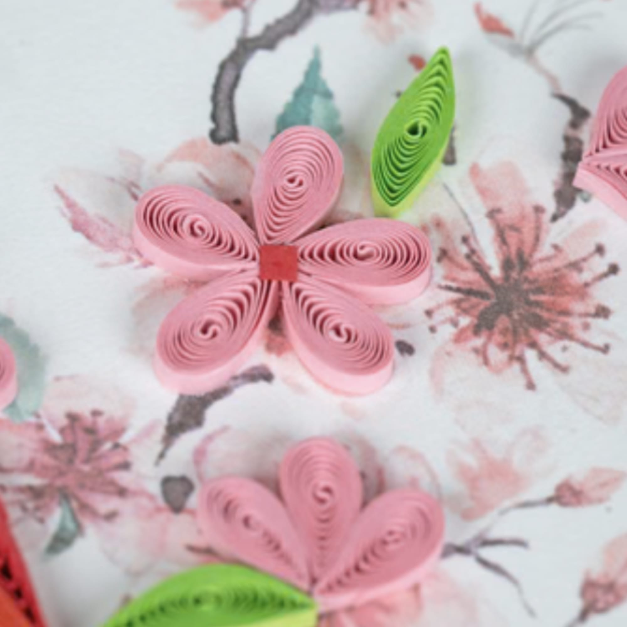 Pink quilled paper flowers with green leaves on a watercolor floral background