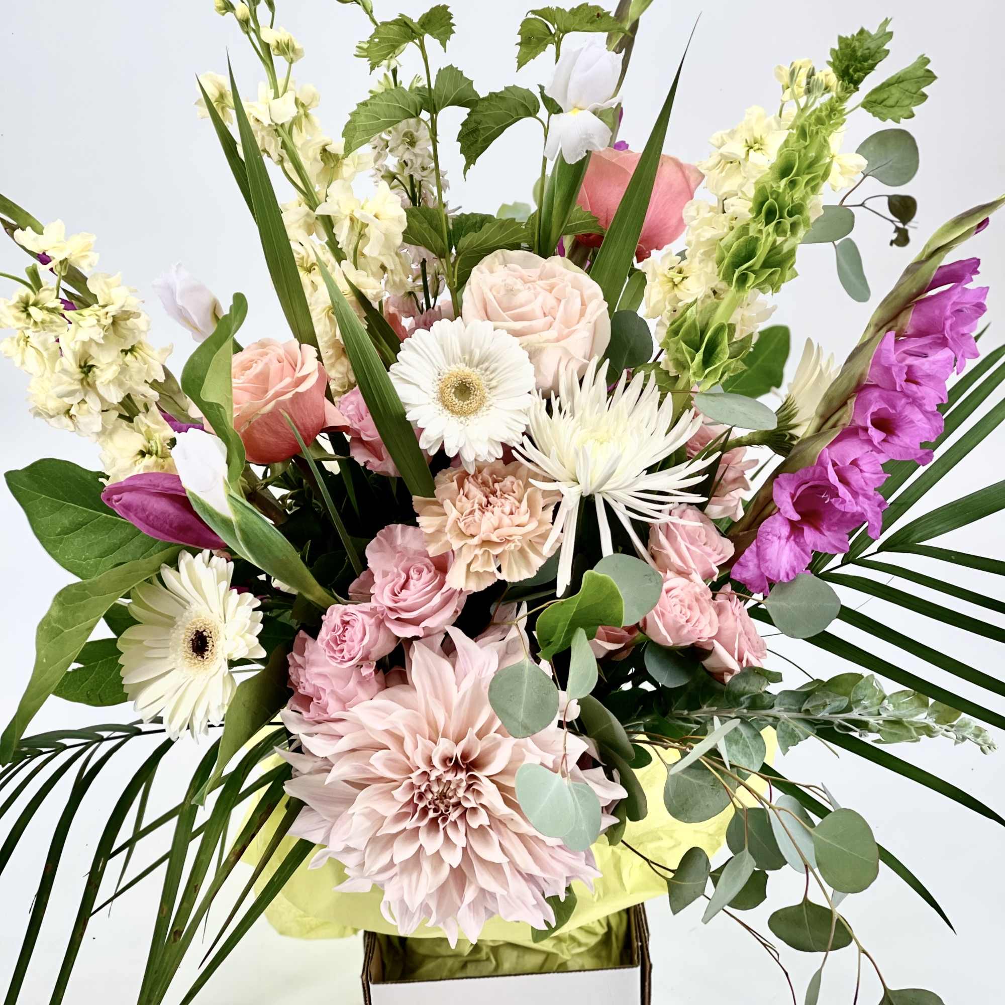 Tall pastel arrangement with pink dahlias, roses, and white gerberas in a white box container.