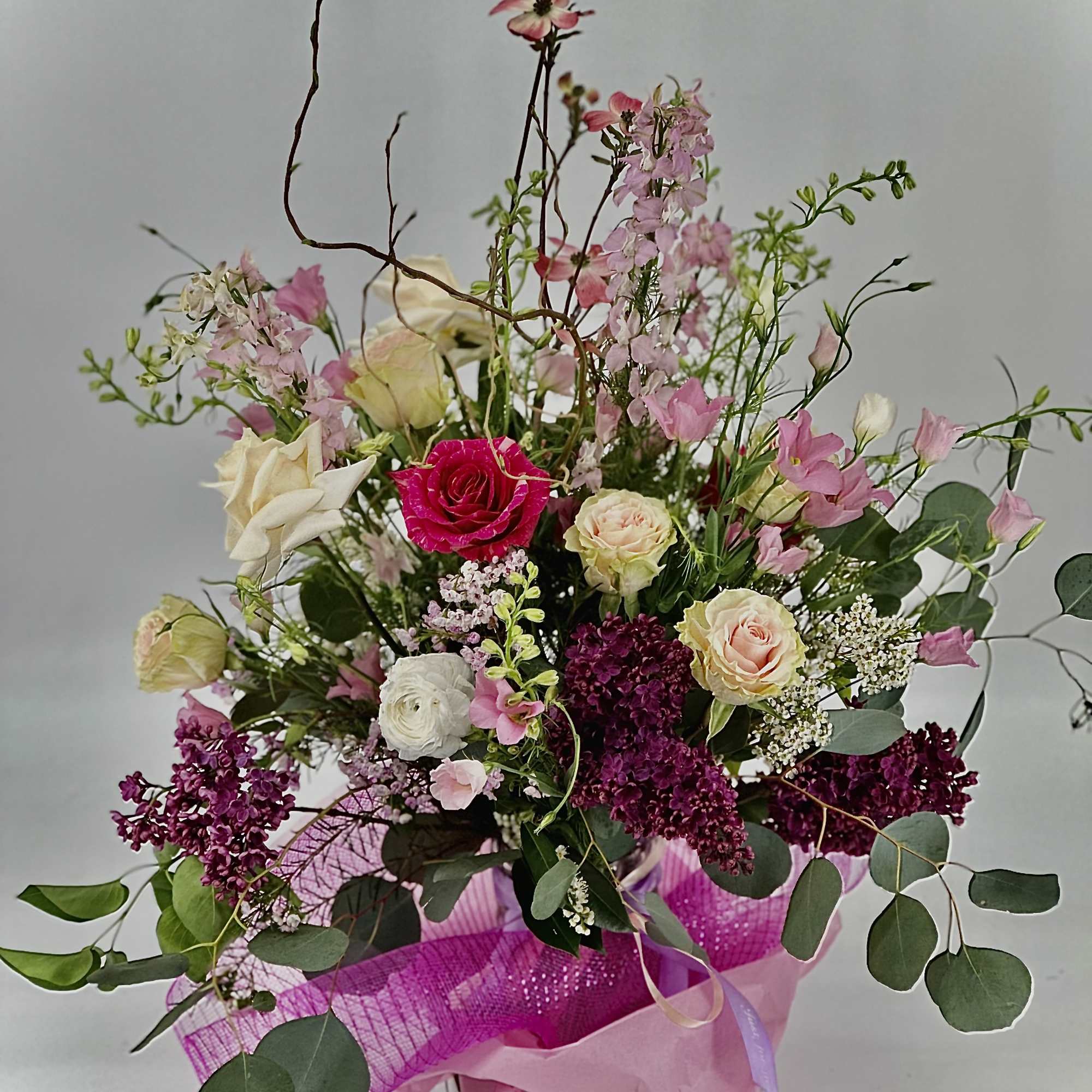 Tall mixed arrangement of pink, white, and burgundy flowers in a white box with pink wrap.