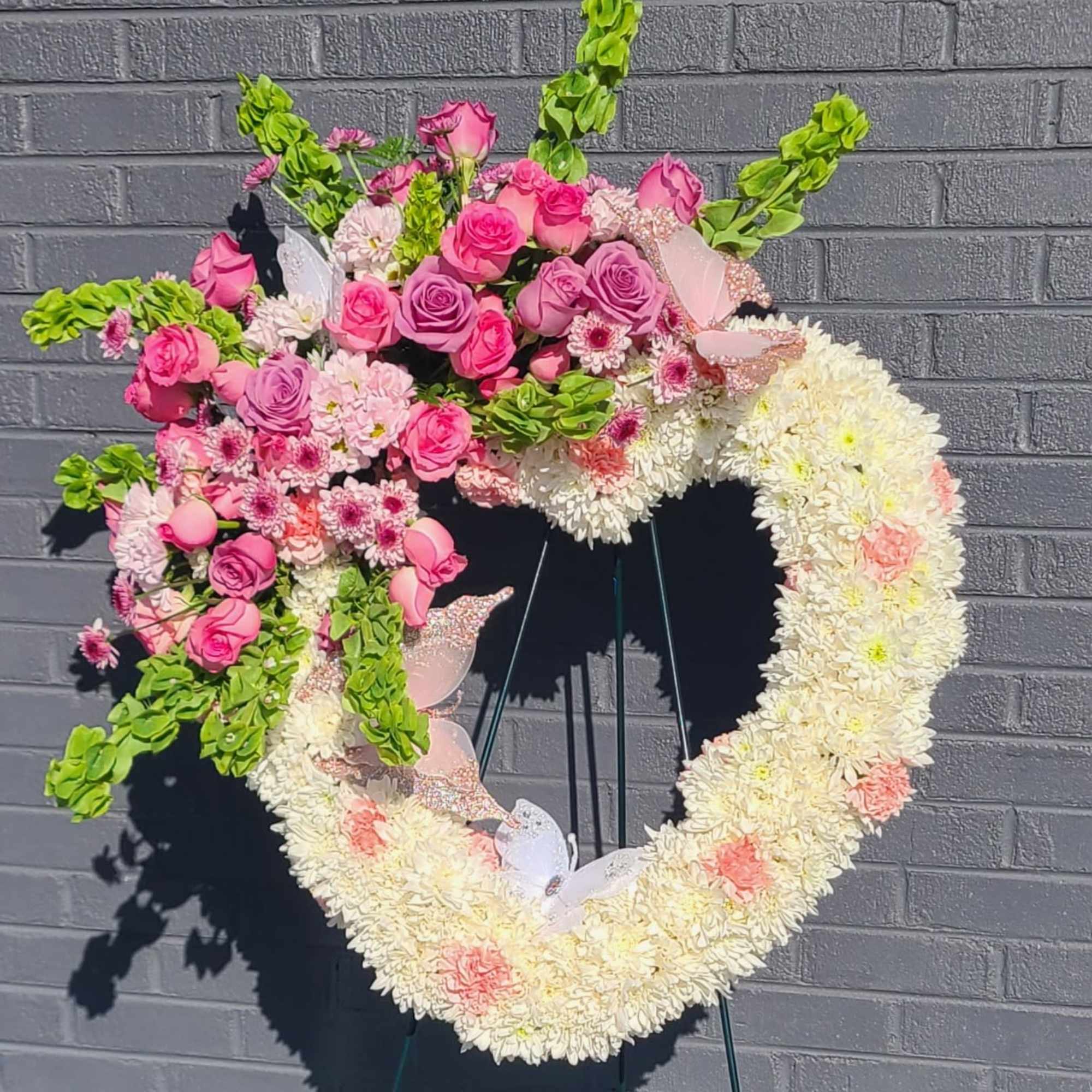 A tender heart-shaped standing spray in soft pinks, whites, lavender accents and