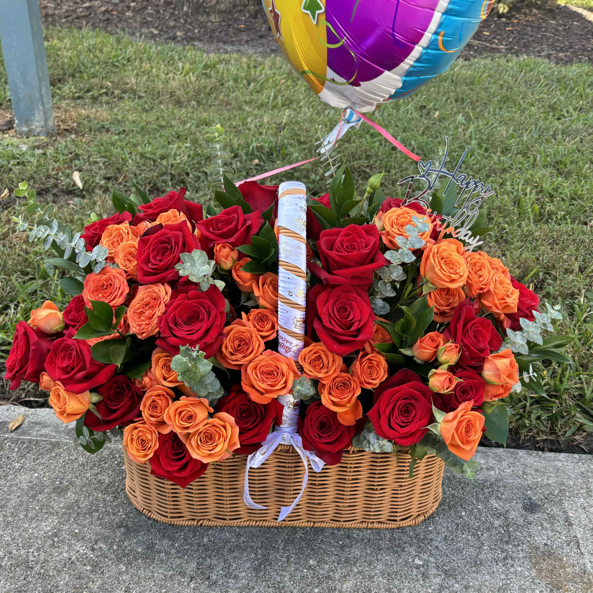 Basket of red and orange roses with a birthday balloon