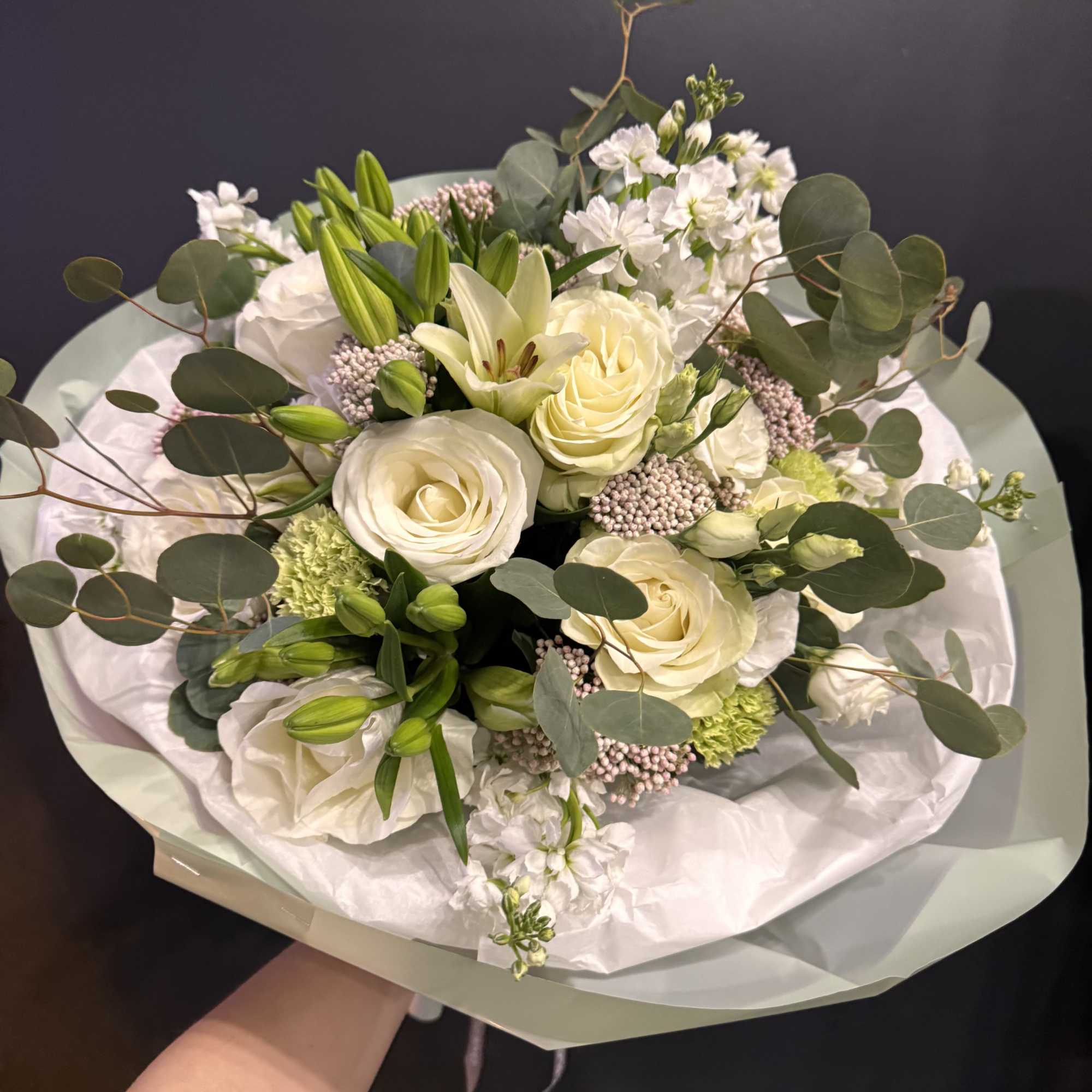 A timeless and elegant arrangement featuring creamy ivory roses, fresh lilies, and