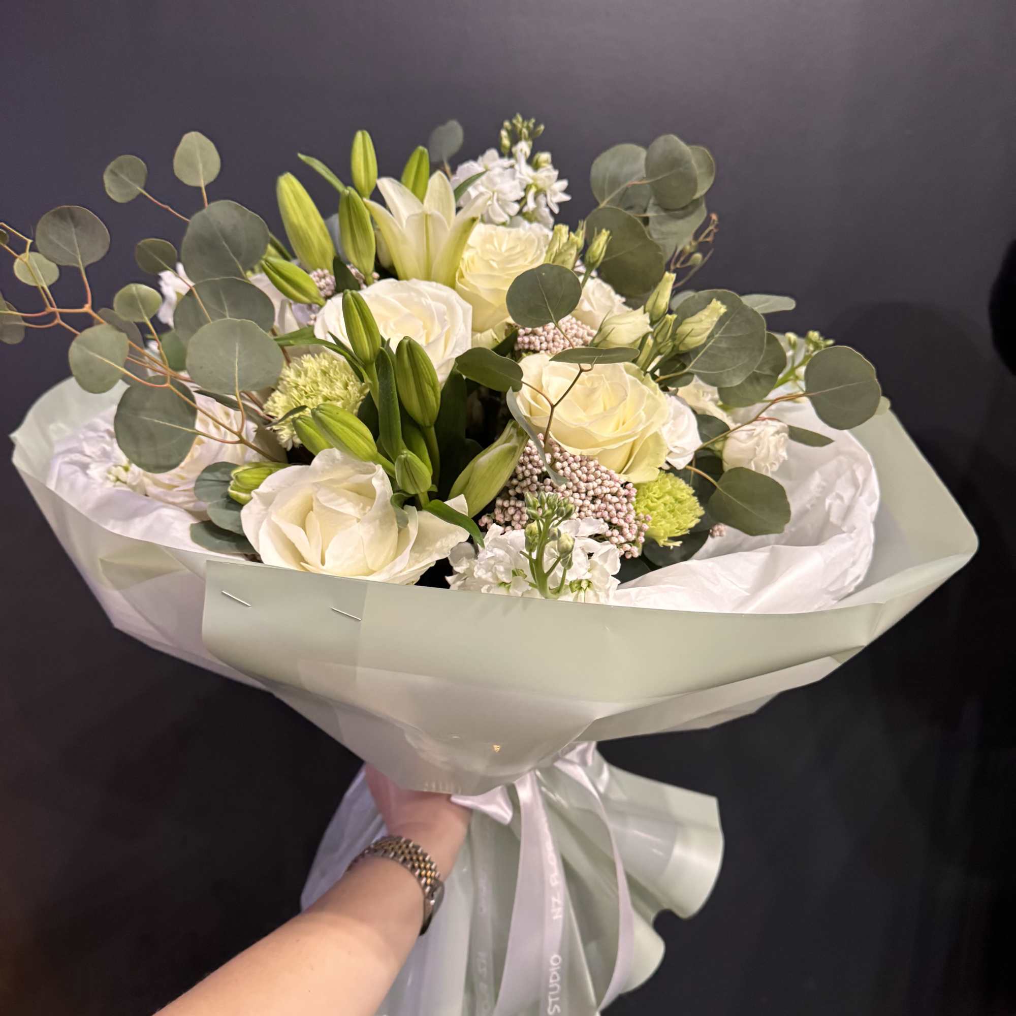 A timeless and elegant arrangement featuring creamy ivory roses, fresh lilies, and
