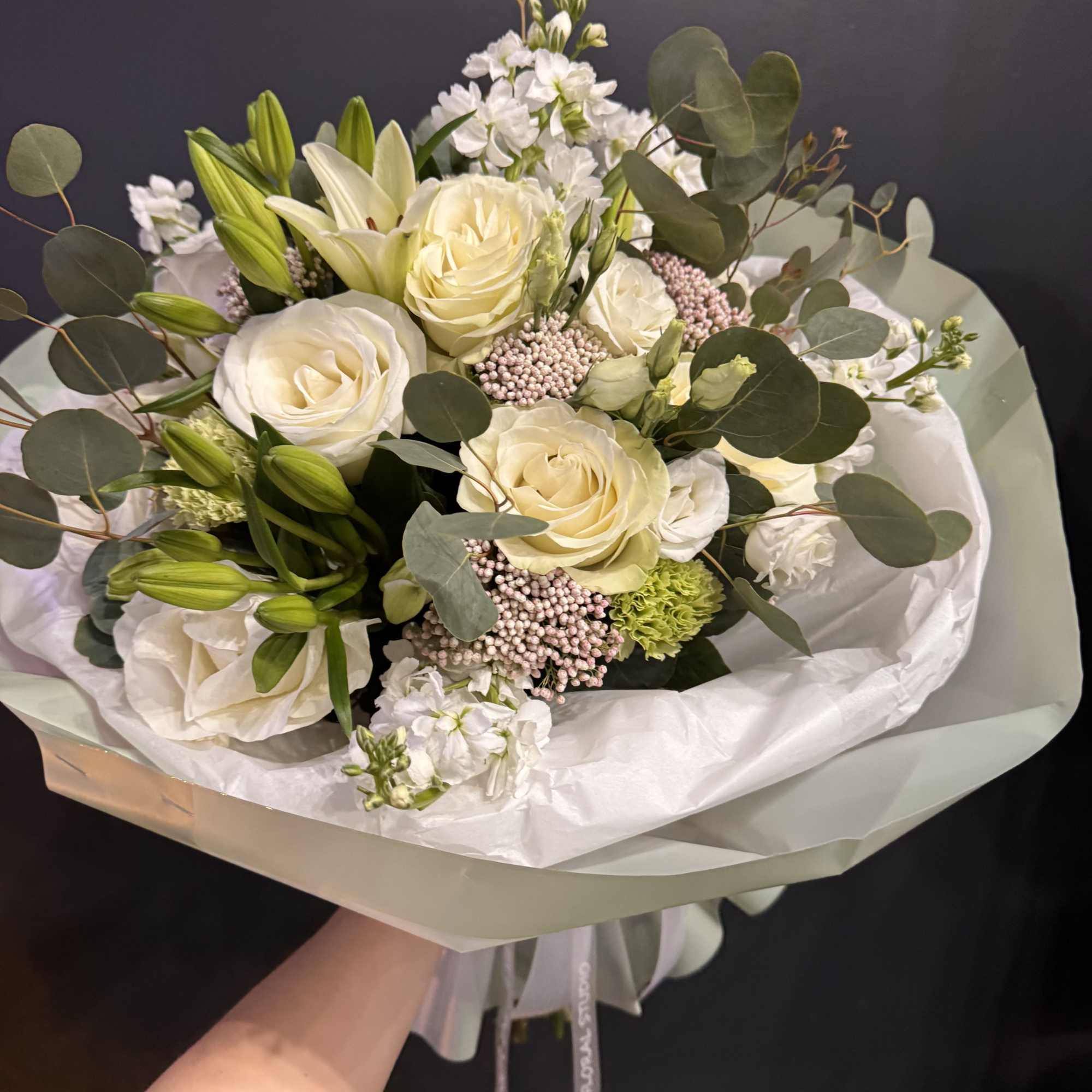 A timeless and elegant arrangement featuring creamy ivory roses, fresh lilies, and