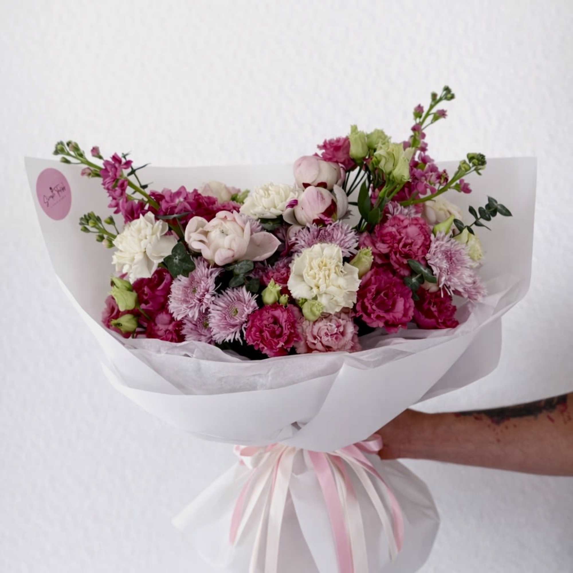 Soft blush peonies and bright pink blooms mingle with creamy white carnations