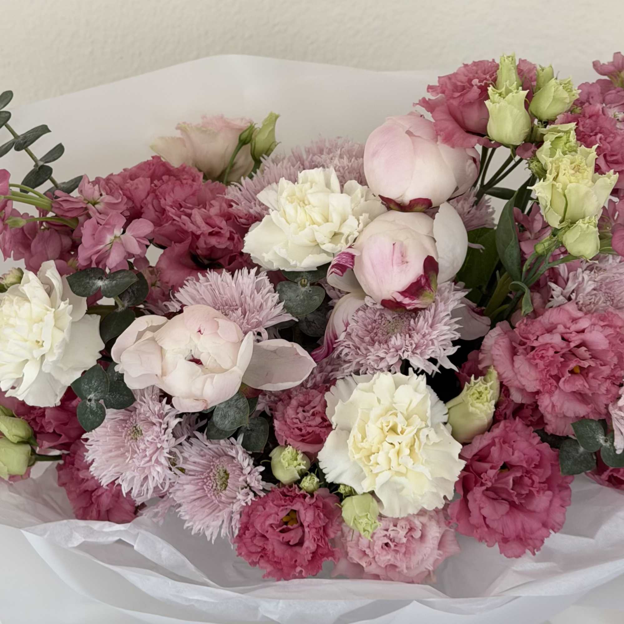 Soft blush peonies and bright pink blooms mingle with creamy white carnations
