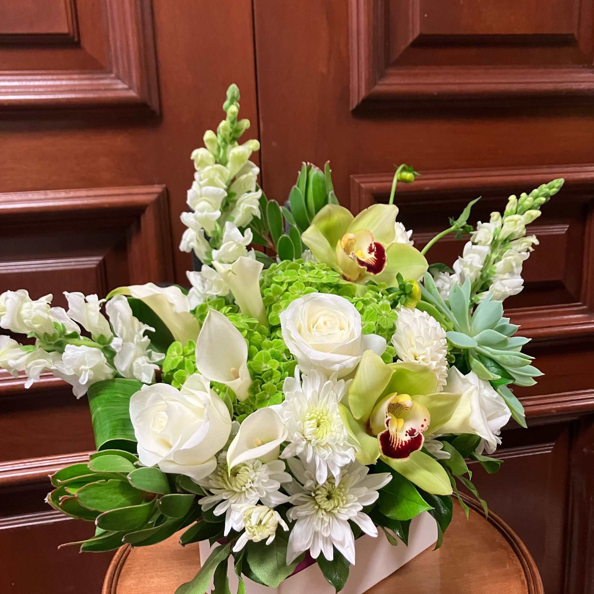 White floral arrangement with orchids, roses, and calla lilies in a white box