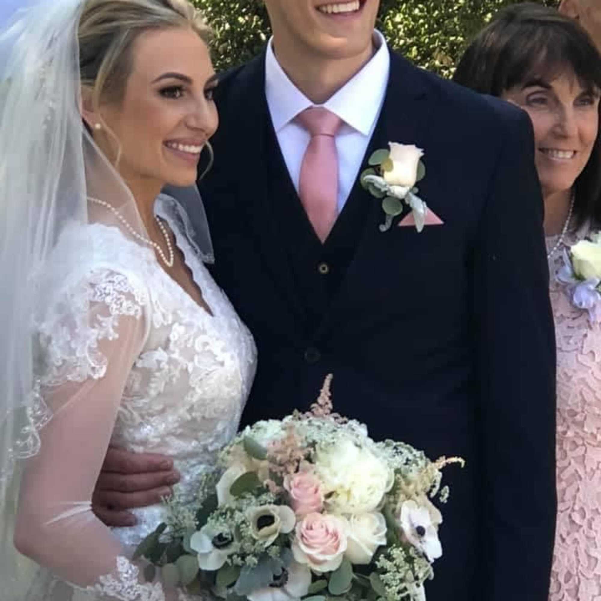 Bride holding a pastel bouquet beside a groom with a white boutonniere