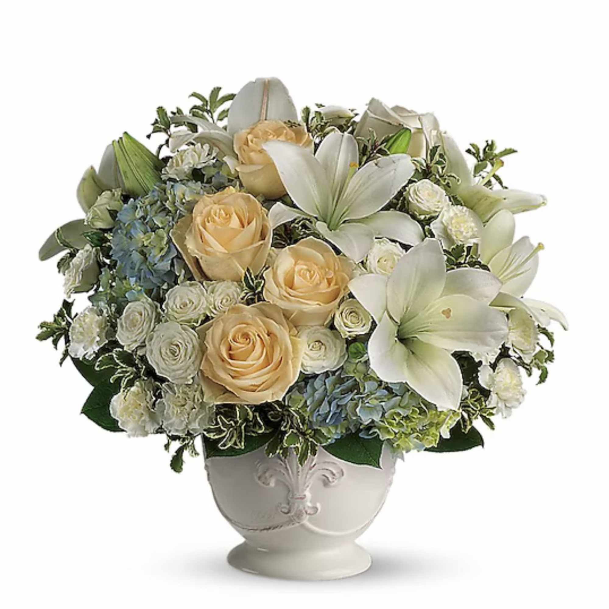 Round arrangement of cream roses, white lilies, and blue hydrangeas in a white ceramic urn