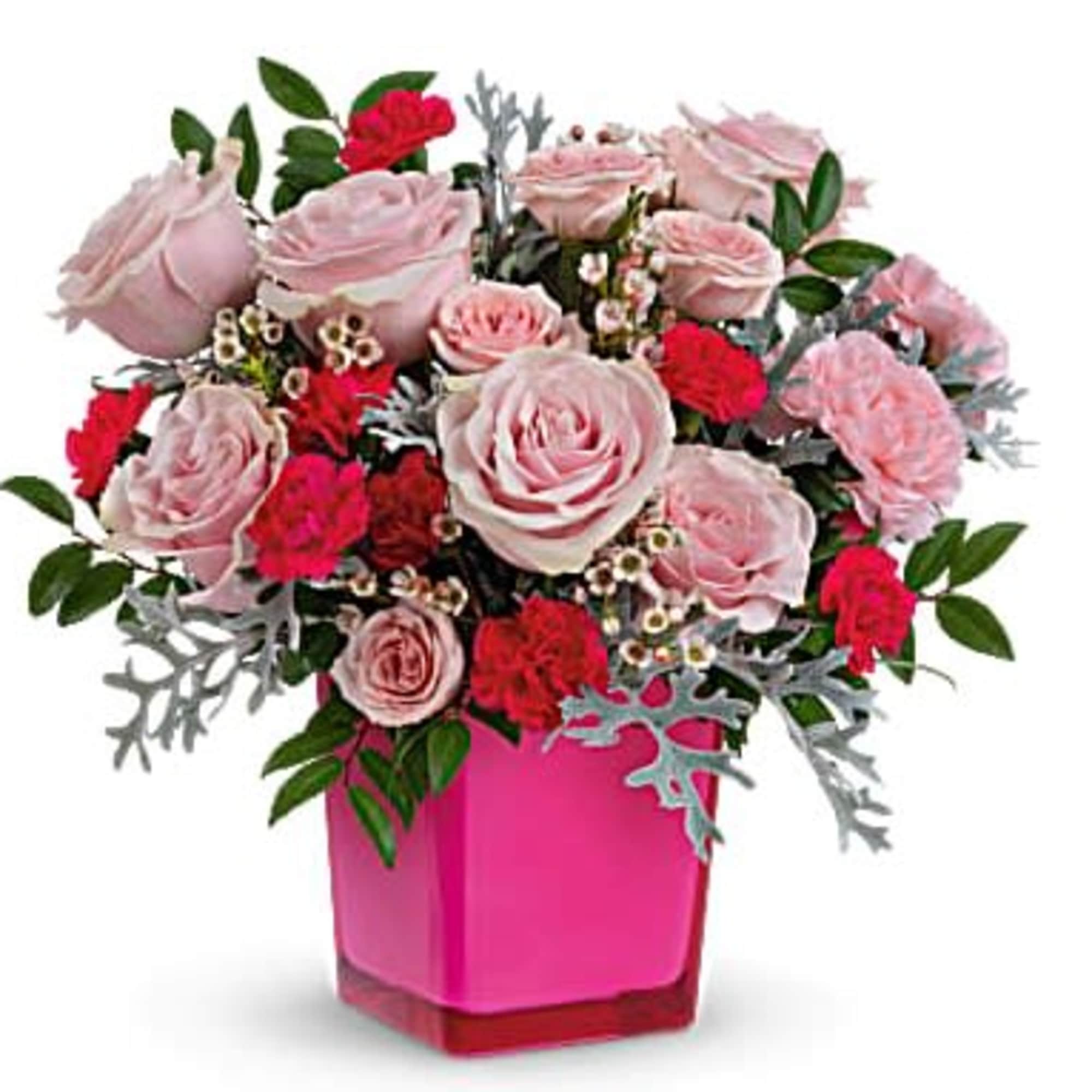 Pink roses and red carnations in a bright pink cube vase with silver-toned accents