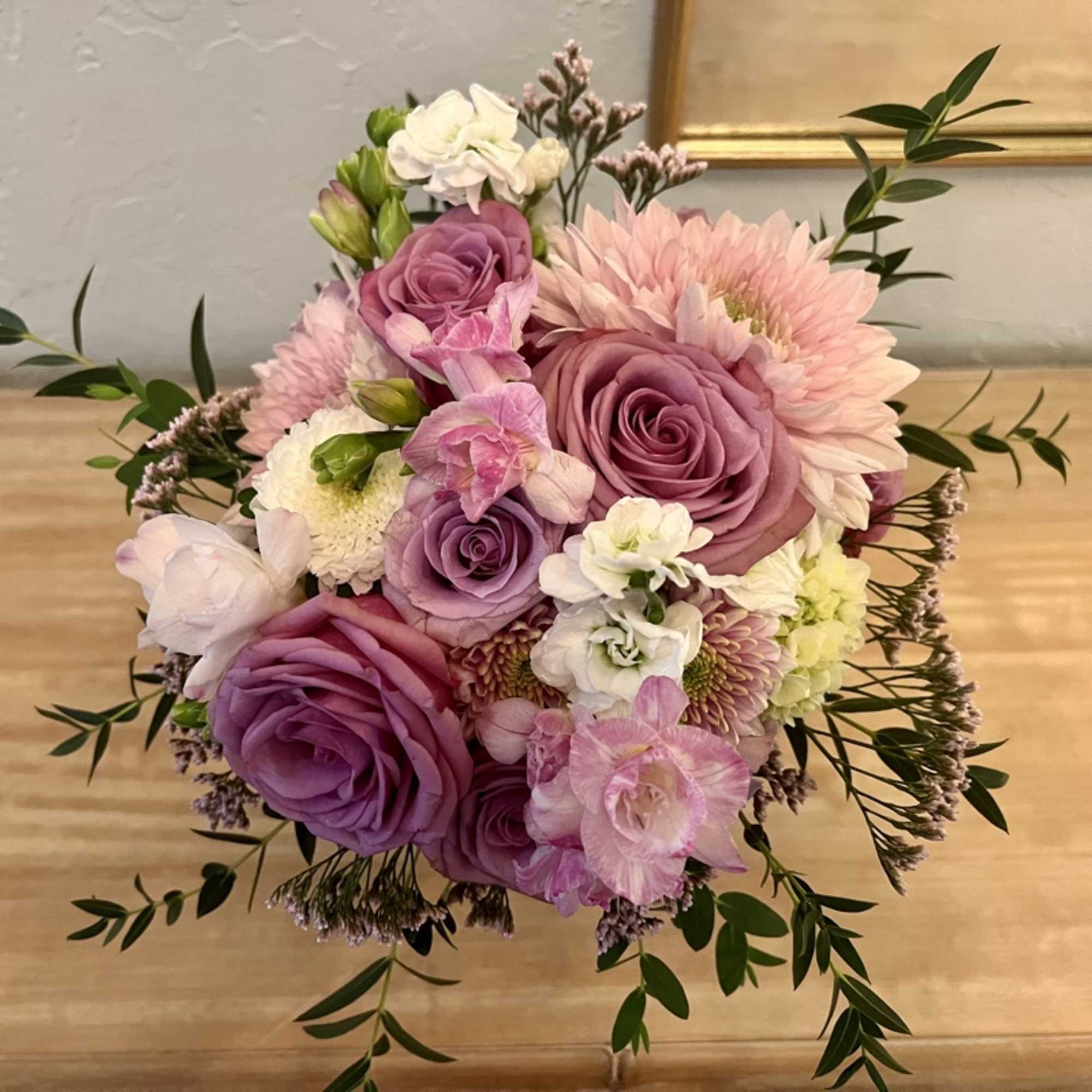Round bouquet of lavender roses with soft pink and white flowers in a compact arrangement