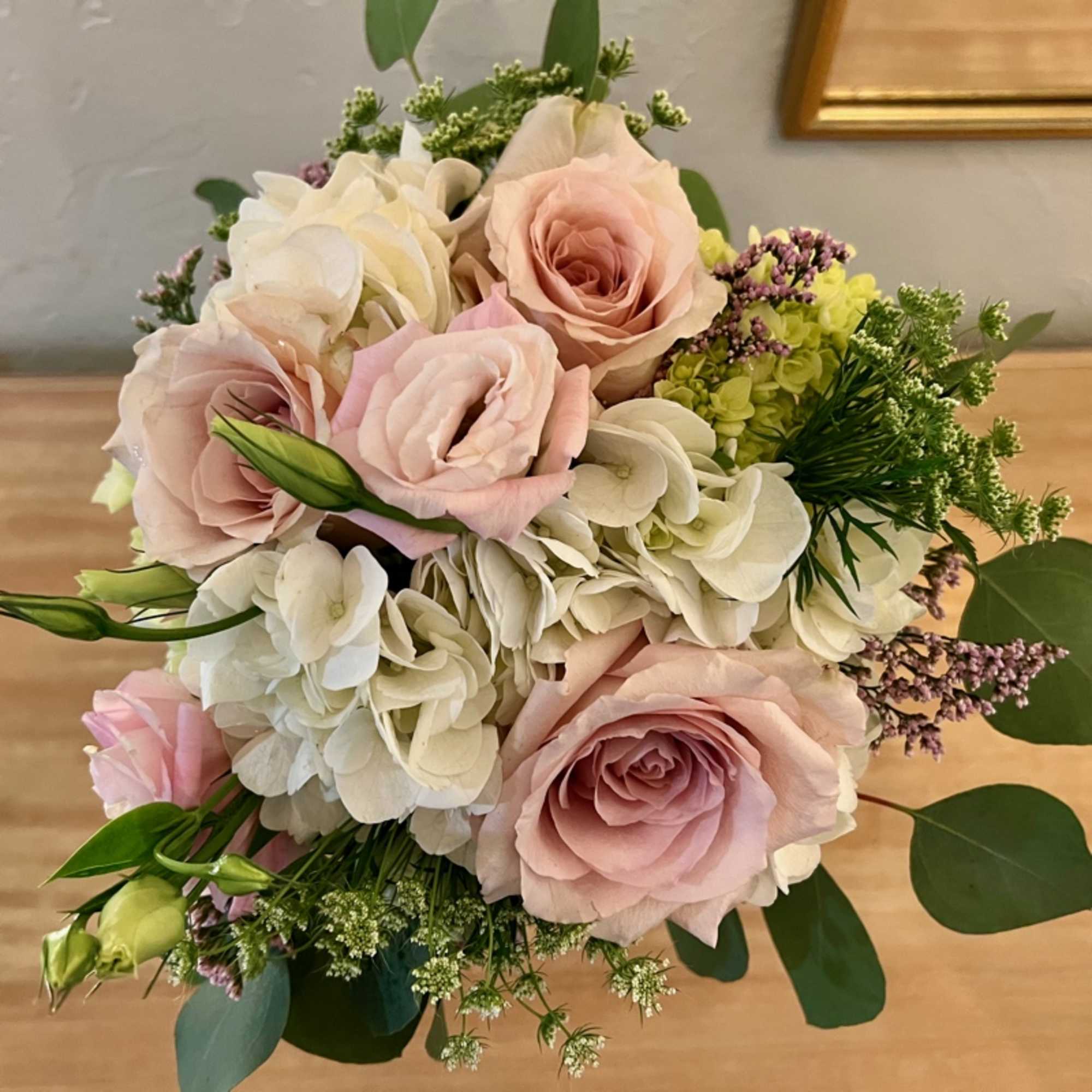 Round bouquet of blush pink roses and white hydrangeas with small green and lavender accents